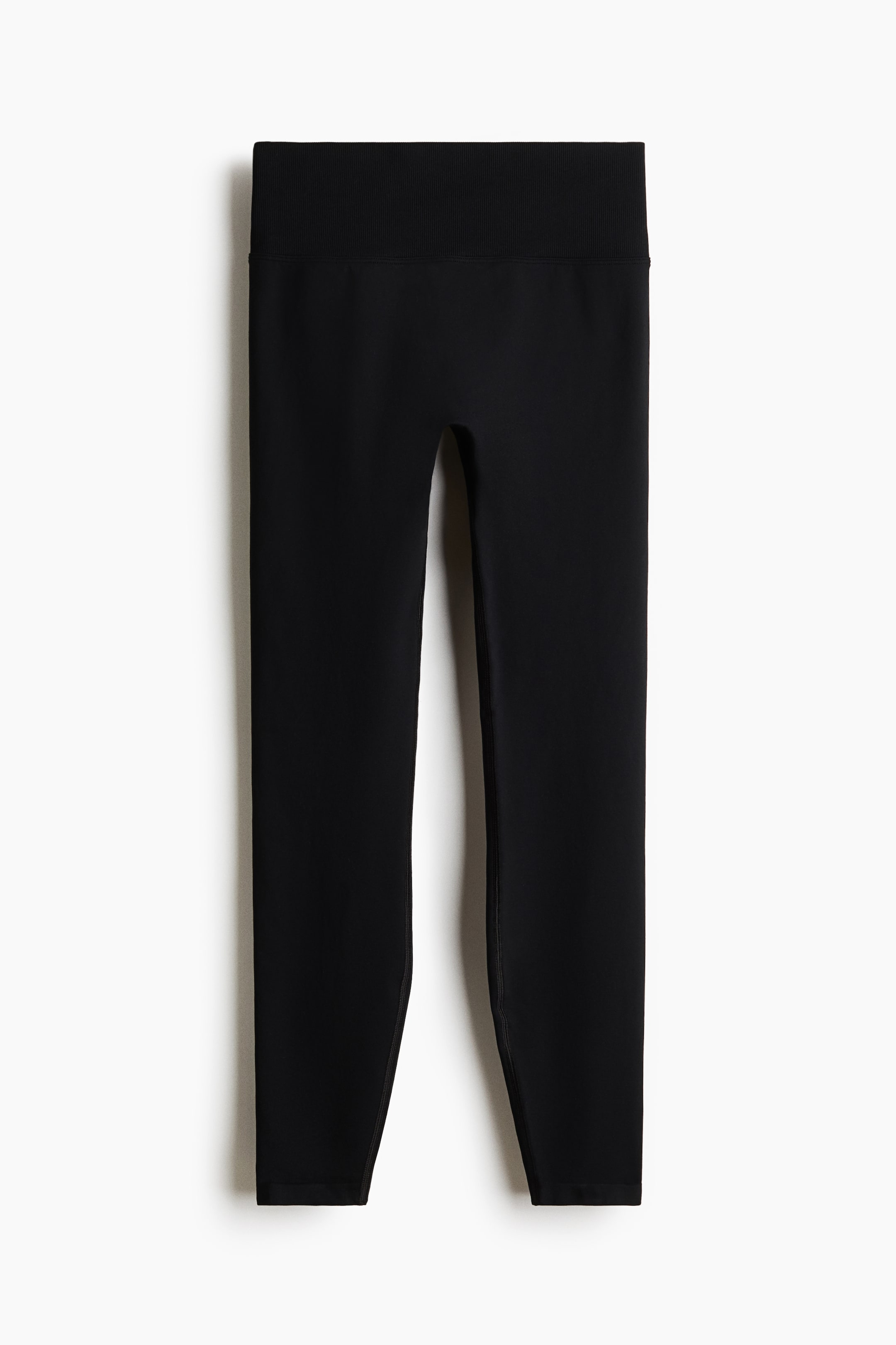 View larger image: Black leggings are showcasing a wide, ribbed high waistband and smooth, tapered legs.