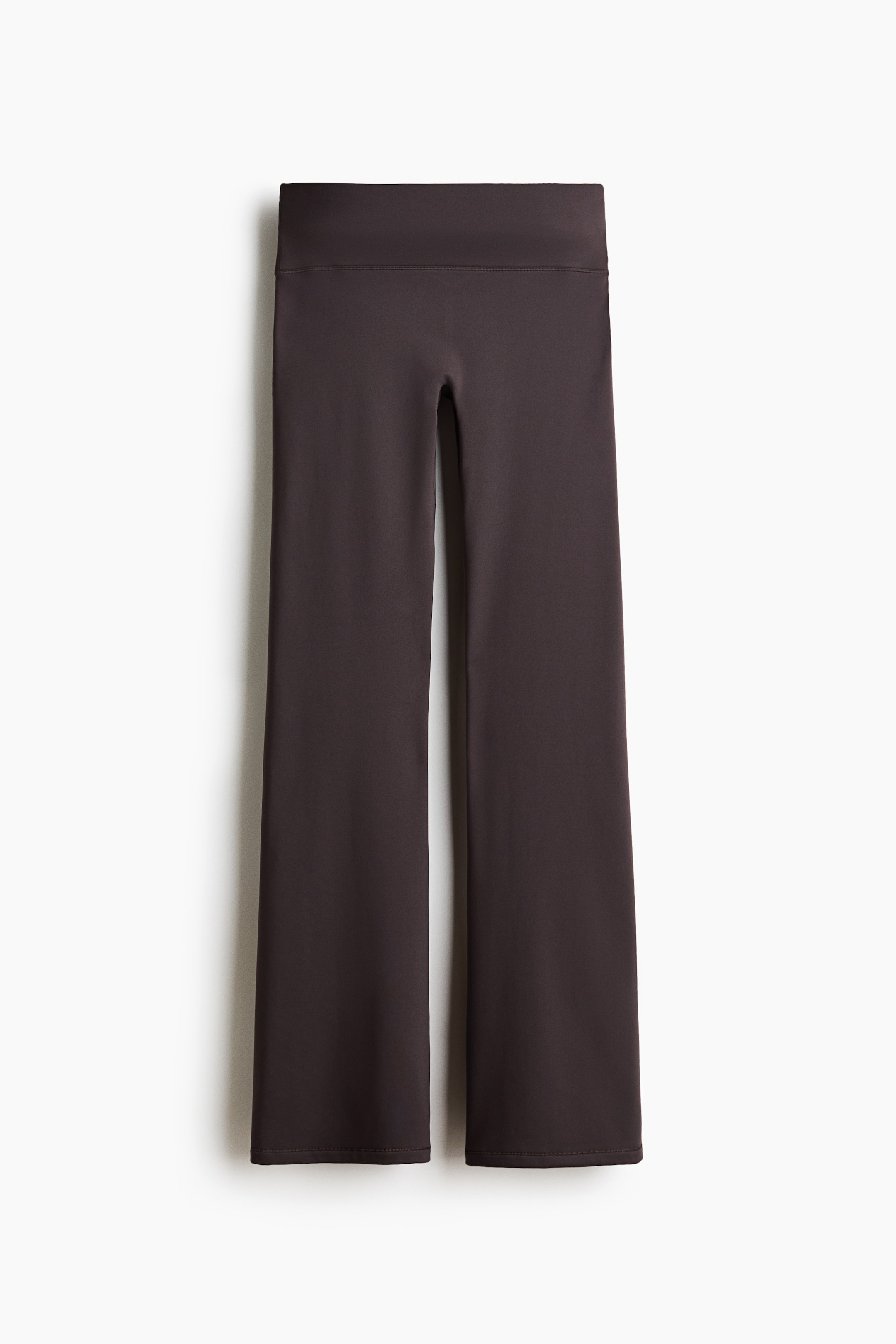 View larger image: A pair of dark brown flared pants is shown from the front, featuring a wide, flat waistband and a smooth, matte finish. The design fits closely through the hips and thighs before widening into a subtle flare at the hems.