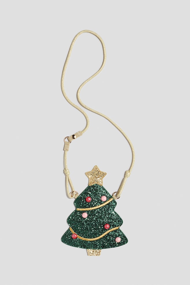 A small, front-facing crossbody bag shaped like a Christmas tree is featuring a green glittery body decorated with small red and pink baubles and curved gold embroidered lines. A gold glitter star is adorning the top of the tree, and a thin, adjustable beige cord strap is looping from the side attachments. - 1