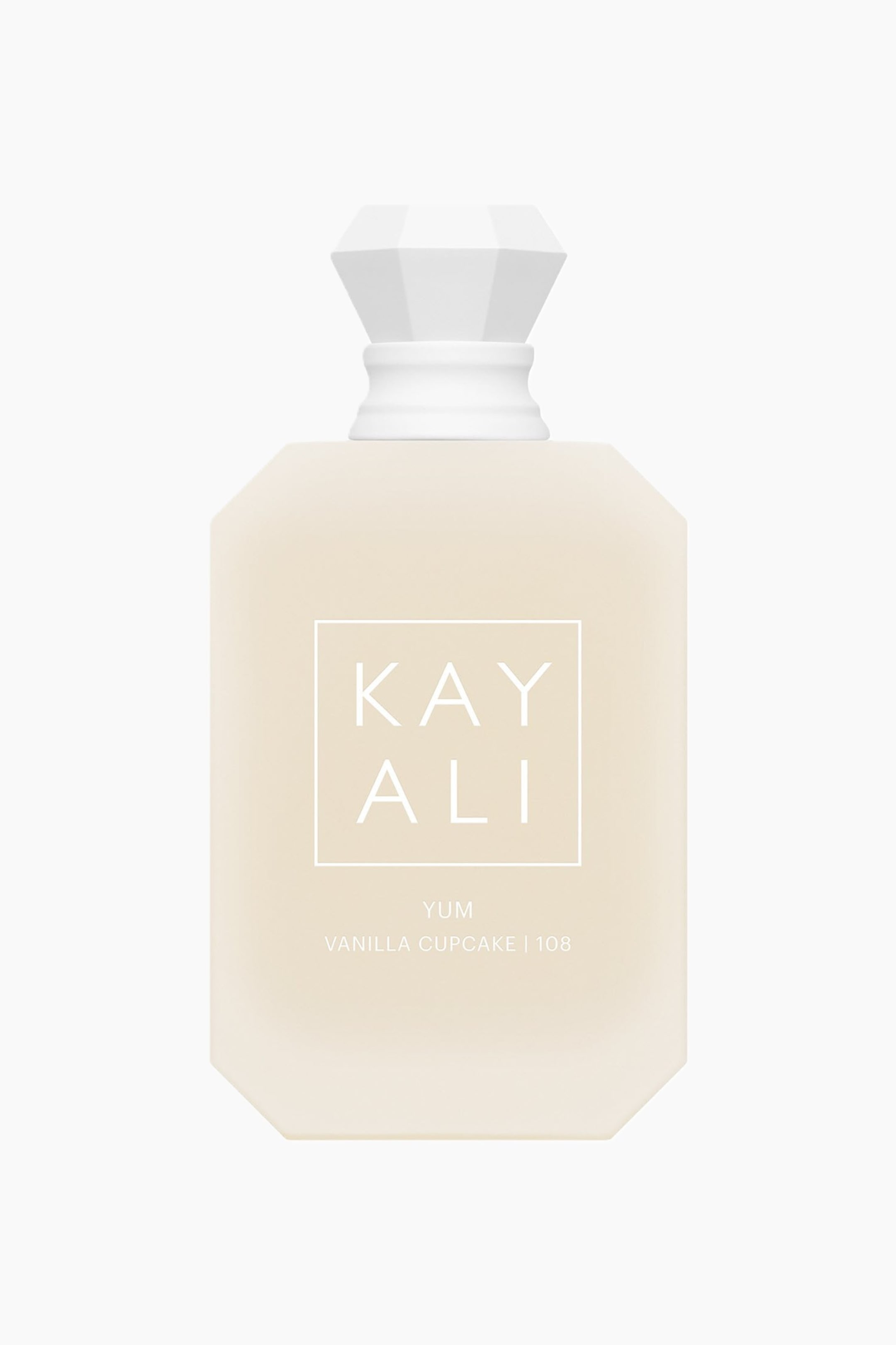 Näytä suurempi kuva: Edestä kuvattu näkymä esittää Kayali Yum Vanilla Cupcake | 108 Eau de Parfum -pulloa, jossa on kuorrutteen näköinen, kahdeksankulmainen kermanvärinen runko. Pullon etupuolella näkyy valkoinen “KAYALI”-logo neliön muotoisen ääriviivan sisällä tekstin “YUM VANILLA CUPCAKE | 108” yläpuolella, ja valkoinen, fasetoitu korumainen korkki lepää uurretun kauluksen päällä.