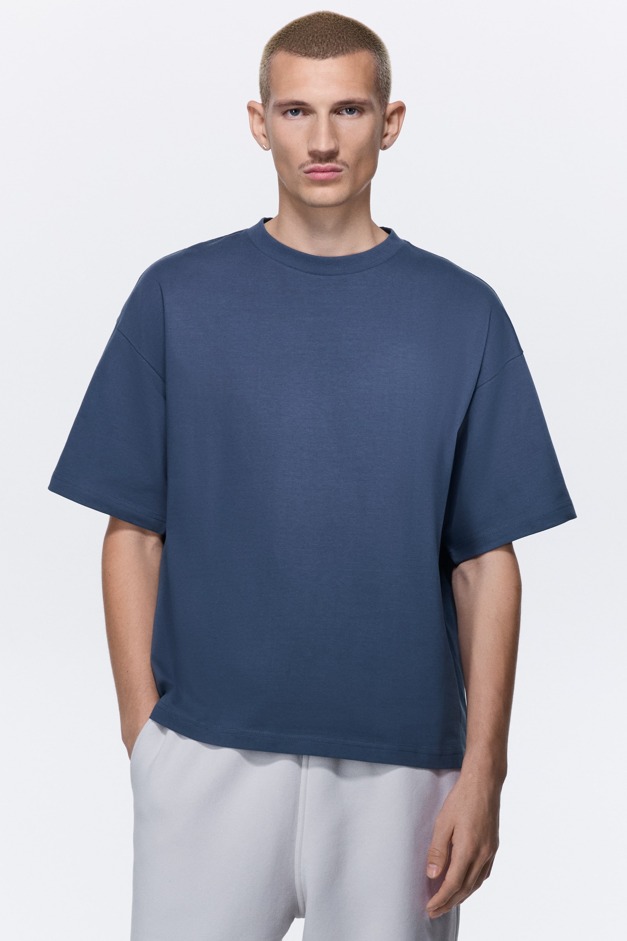 View larger image: The slate blue t-shirt is facing directly forward, presenting an oversized fit with dropped shoulders and wide, short sleeves, while featuring a crew neck and a straight hem.