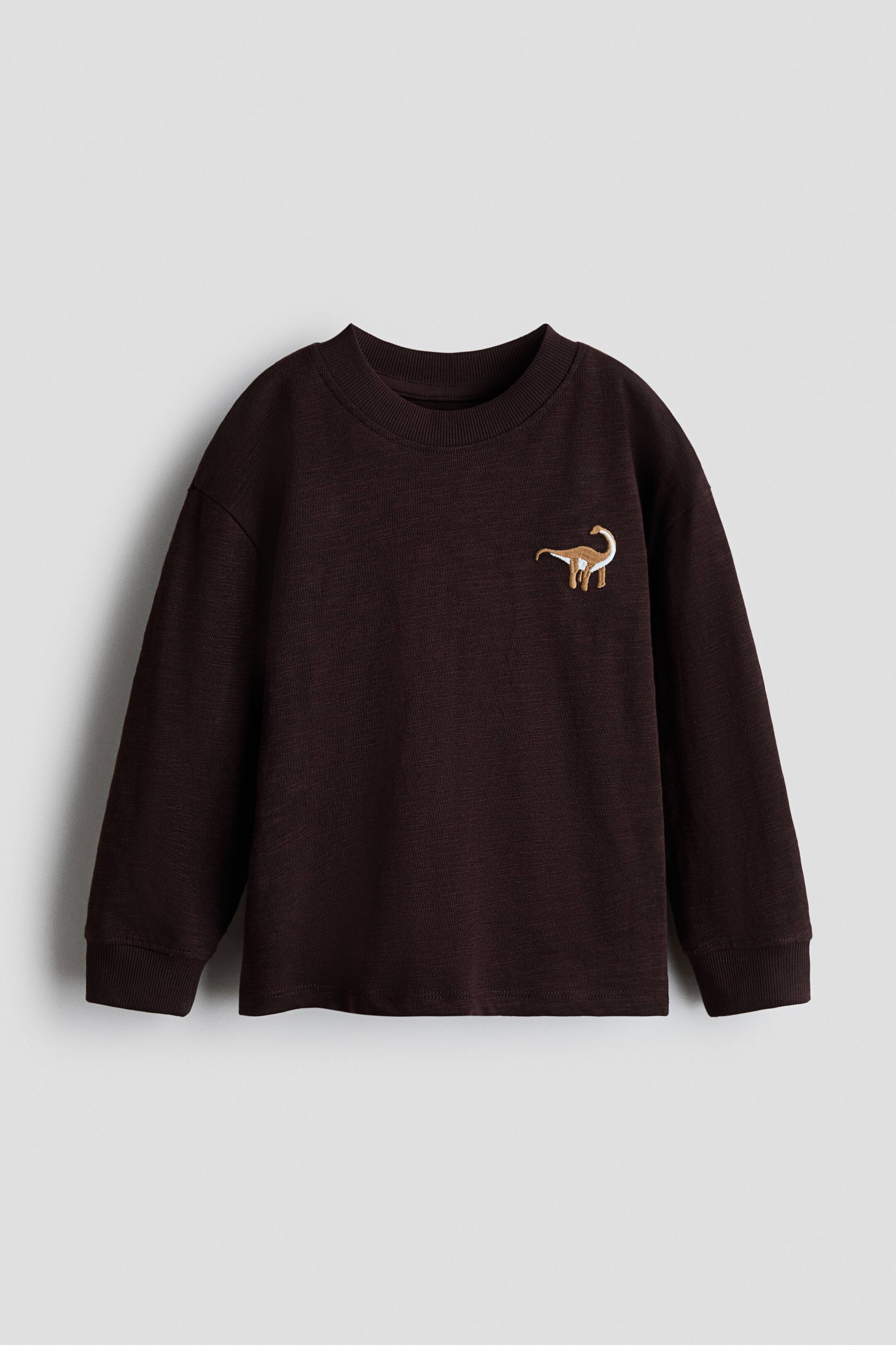 View larger image: A dark brown long-sleeved crewneck jumper is presented facing front, featuring a light brown embroidered dinosaur on the left chest and ribbed cuffs and hem.