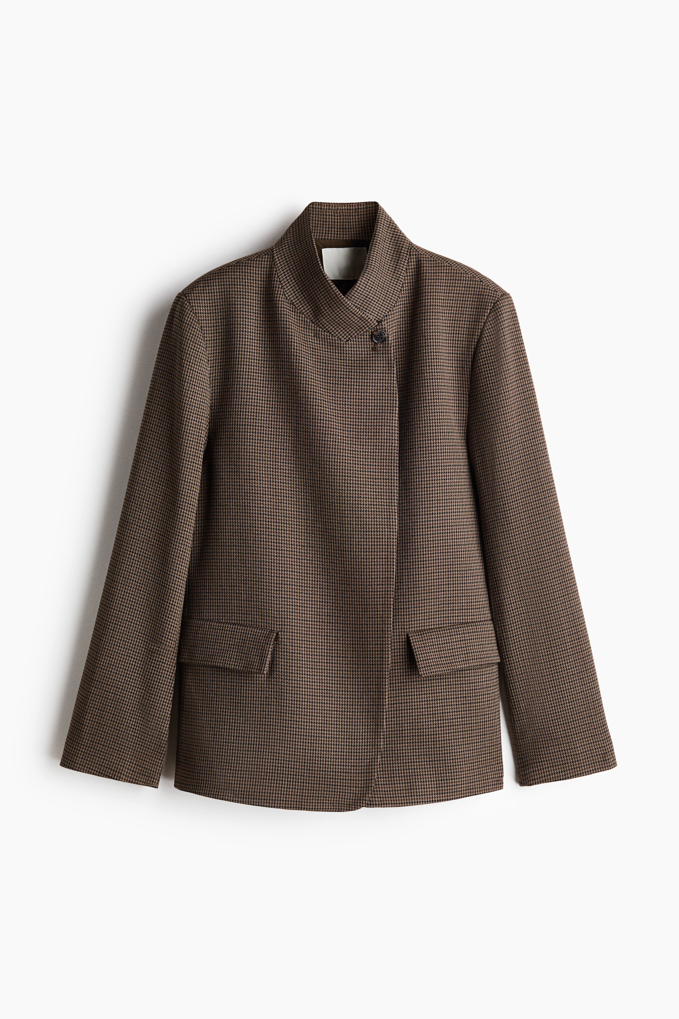 View larger image: A brown and black houndstooth pattern jacket is showcased from a front-facing, slightly angled perspective. It features a standing collar with a V-neck opening, an asymmetrical front closure secured by one visible button, and two front flap pockets.