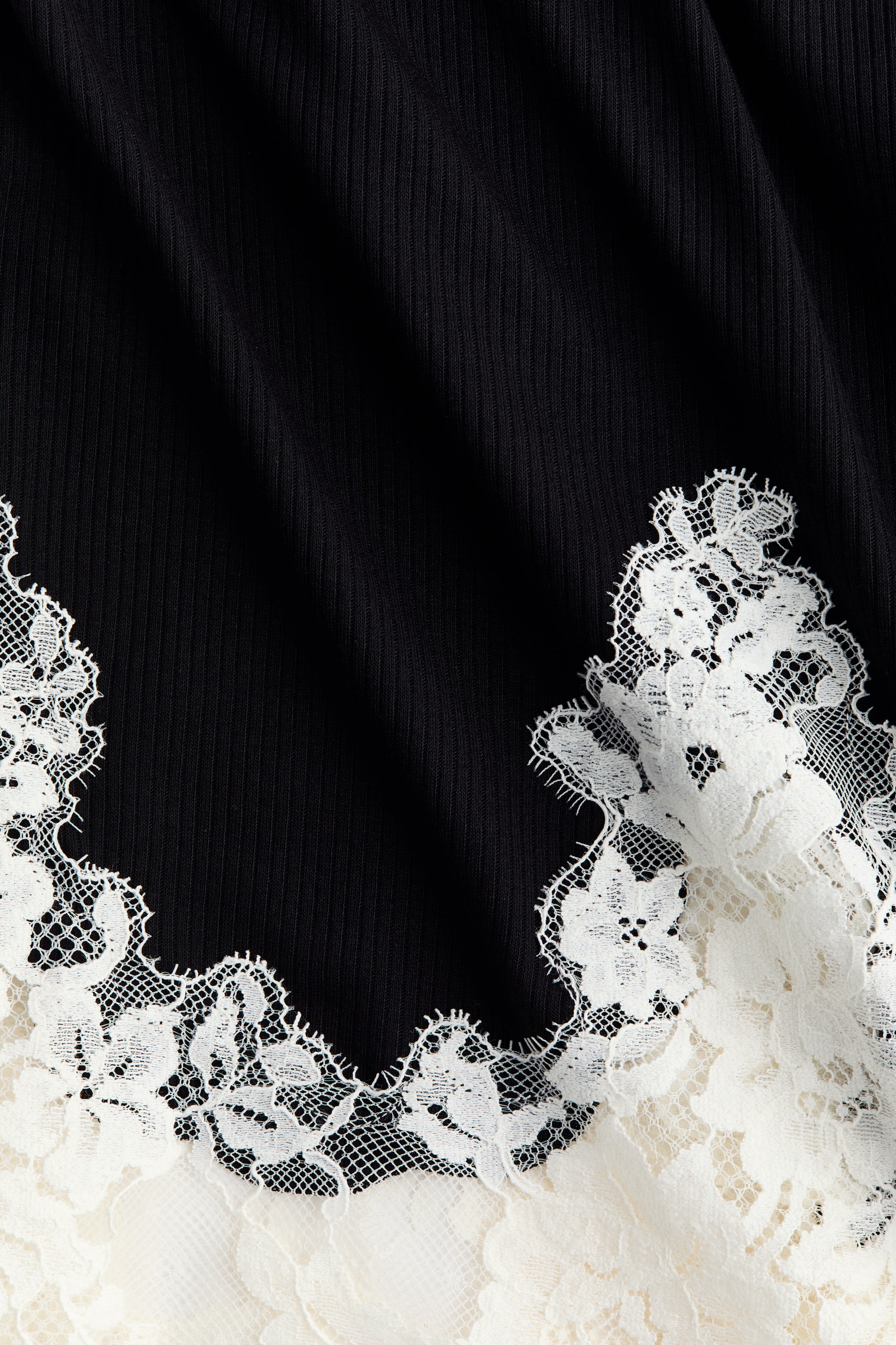 Voir une image plus grande: Les pantalons de pyjama sont en jersey côtelé noir, agrémentés d'une large bordure en dentelle blanche à l'ourlet.
