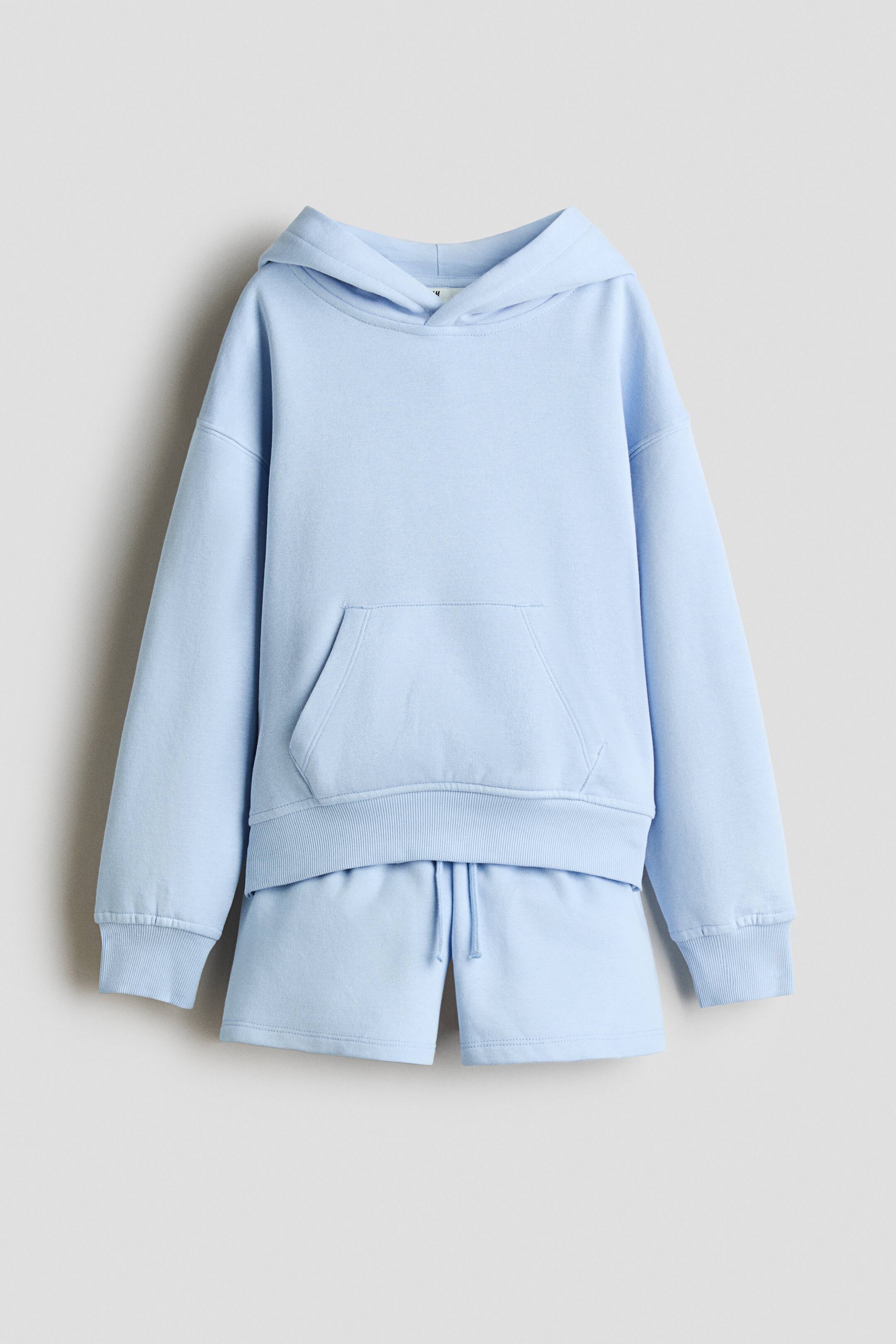 View larger image: A light blue loungewear set is shown front-facing, featuring a long-sleeved hoodie and matching shorts. The hoodie has a front kangaroo pocket, ribbed cuffs, and a ribbed hem, while the matching shorts feature a drawstring waistband.