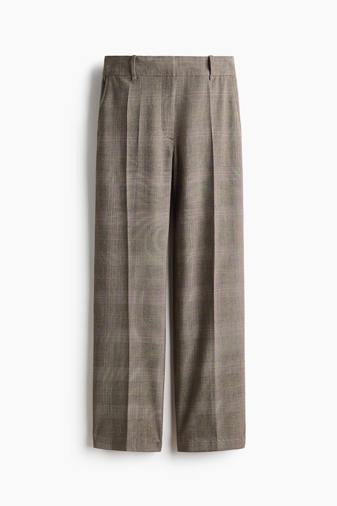 These loose-fit tailored trousers in a brown plaid twill are shown from the front, featuring straight legs with sharp, defined creases running down the centre. The design includes diagonal side pockets, belt loops, and a flat front waistband with a concealed fastening. - 1