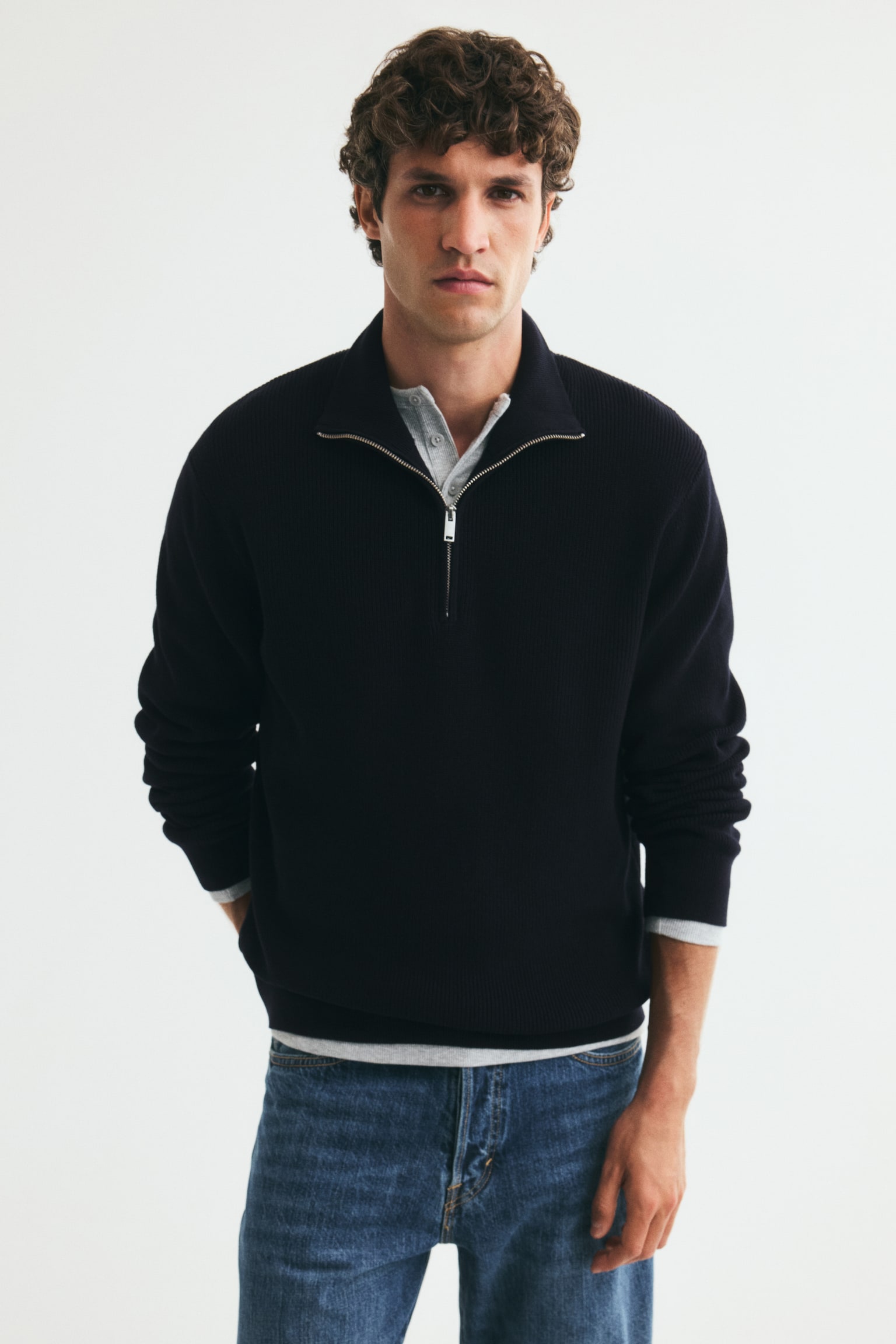 A dark blue quarter-zip jumper is facing forward, featuring a standing collar and a silver-toned zip. The jumper displays a ribbed knit texture on the upper body and a smoother knit on the lower body and long sleeves. - 1