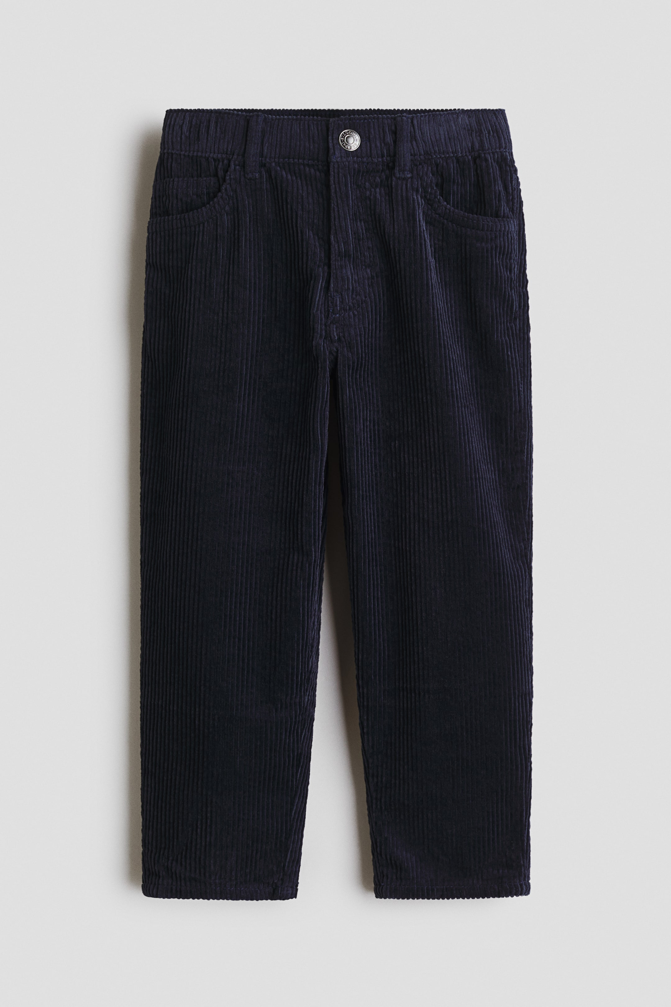 View larger image: Dark blue corduroy trousers are displayed front-facing, featuring a relaxed fit through the hip, thigh, and leg. They showcase an elasticated waistband with a central press-stud closure and zip fly, along with two curved front pockets and a visible coin pocket.
