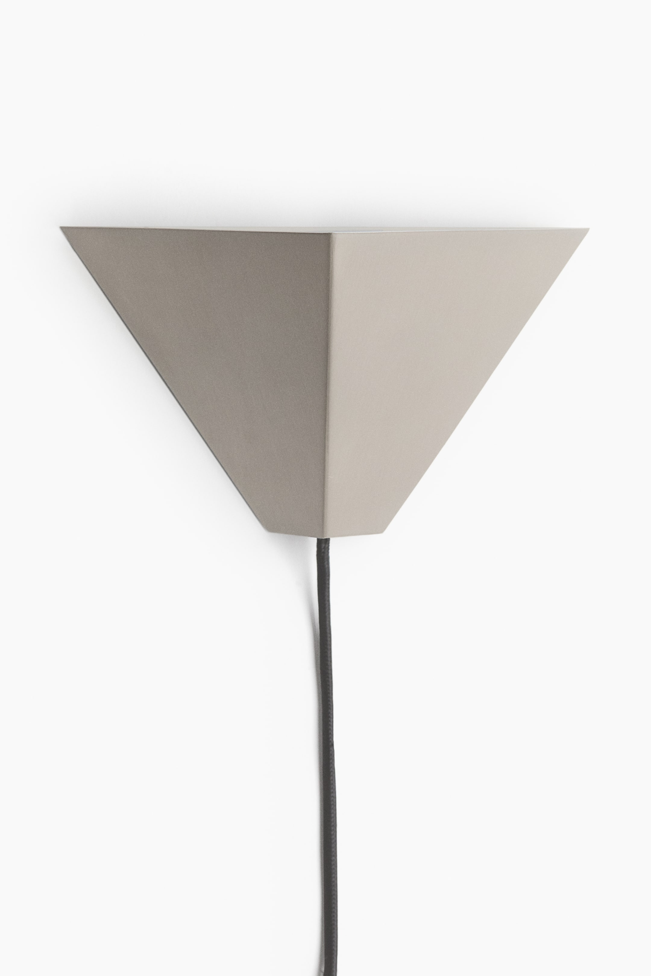 View larger image: A wall lamp is shown facing the front, featuring a geometric, inverted triangular shade with a matt greige finish. A dark grey cord extends downwards from the flat base of the tapered structure.