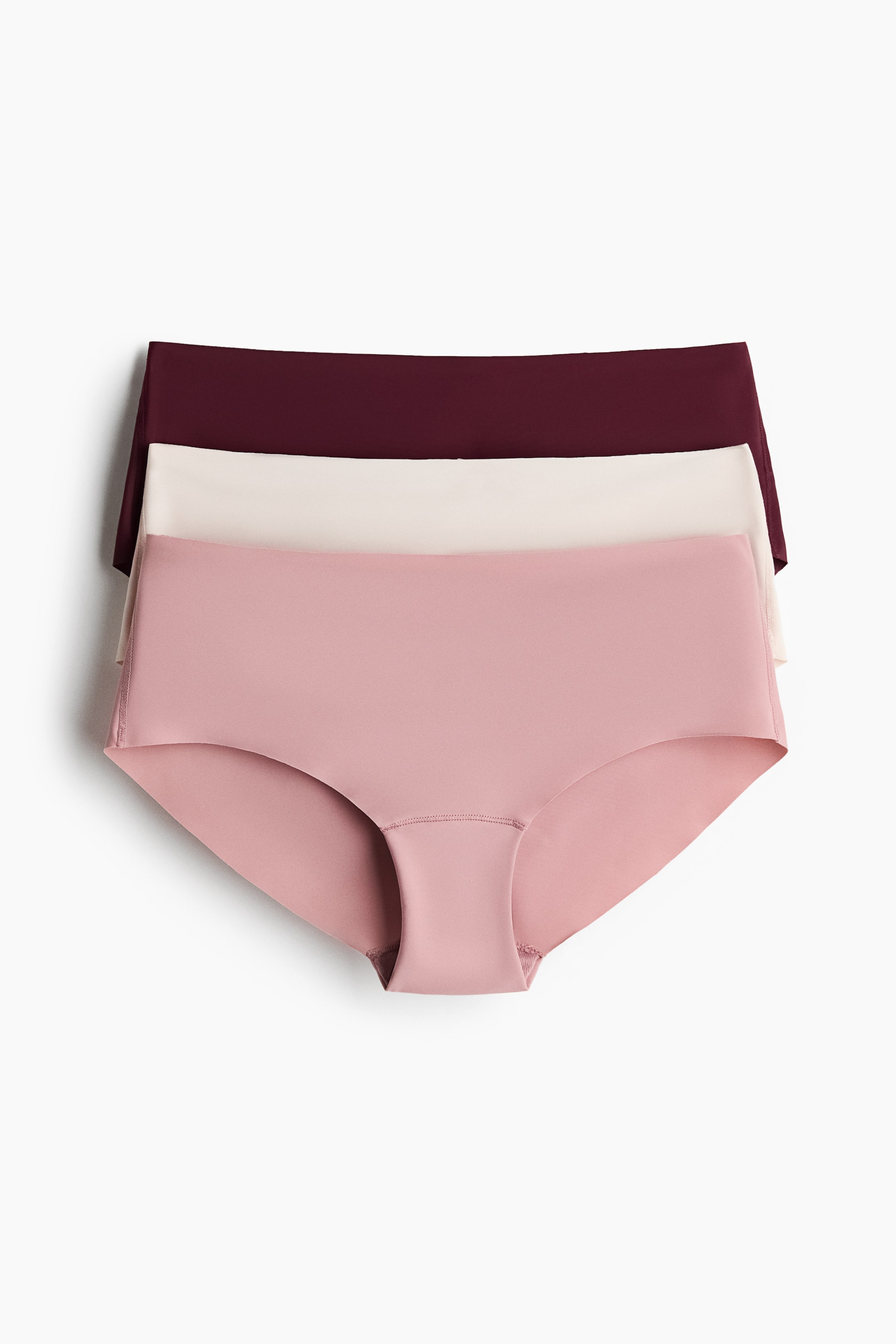 Ver imagen más grande: Tres pares de braguitas hipster sin costuras están dispuestas en capas, con colores burdeos, beige y rosa apareciendo de arriba a abajo. La braguita rosa inferior está colocada plana y mirando hacia adelante, mostrando sus bordes lisos cortados con láser y su cobertura moderada.