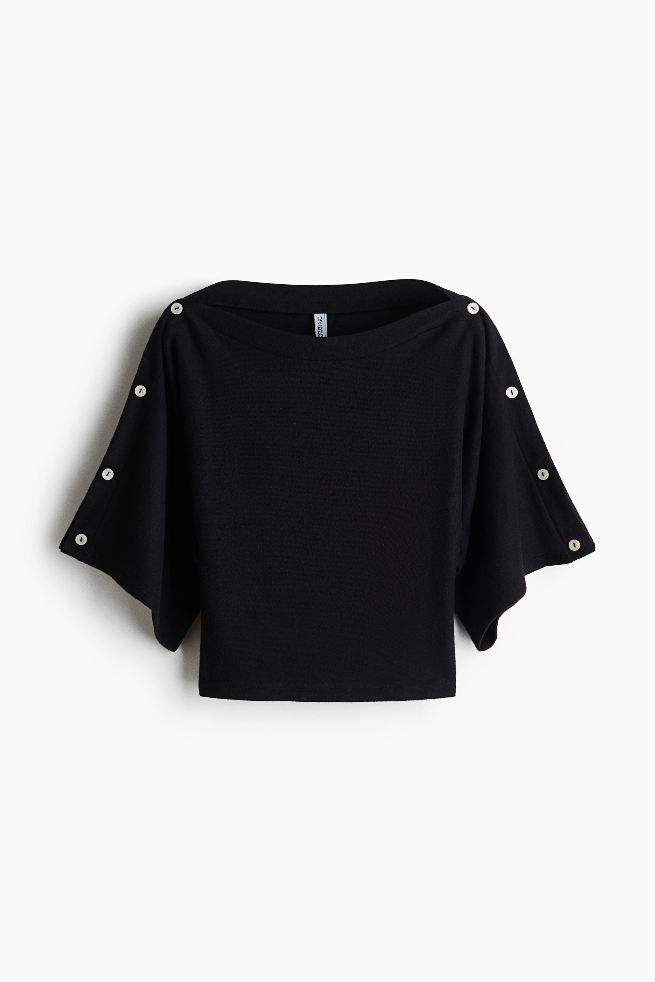 Zobrazit větší obrázek: Černý crop top je zobrazen zepředu, s širokým lodkovým výstřihem a volnými, splývavými krátkými rukávy. Podél horních švů ramen a rukávů jsou umístěna malá světlá knoflíky.