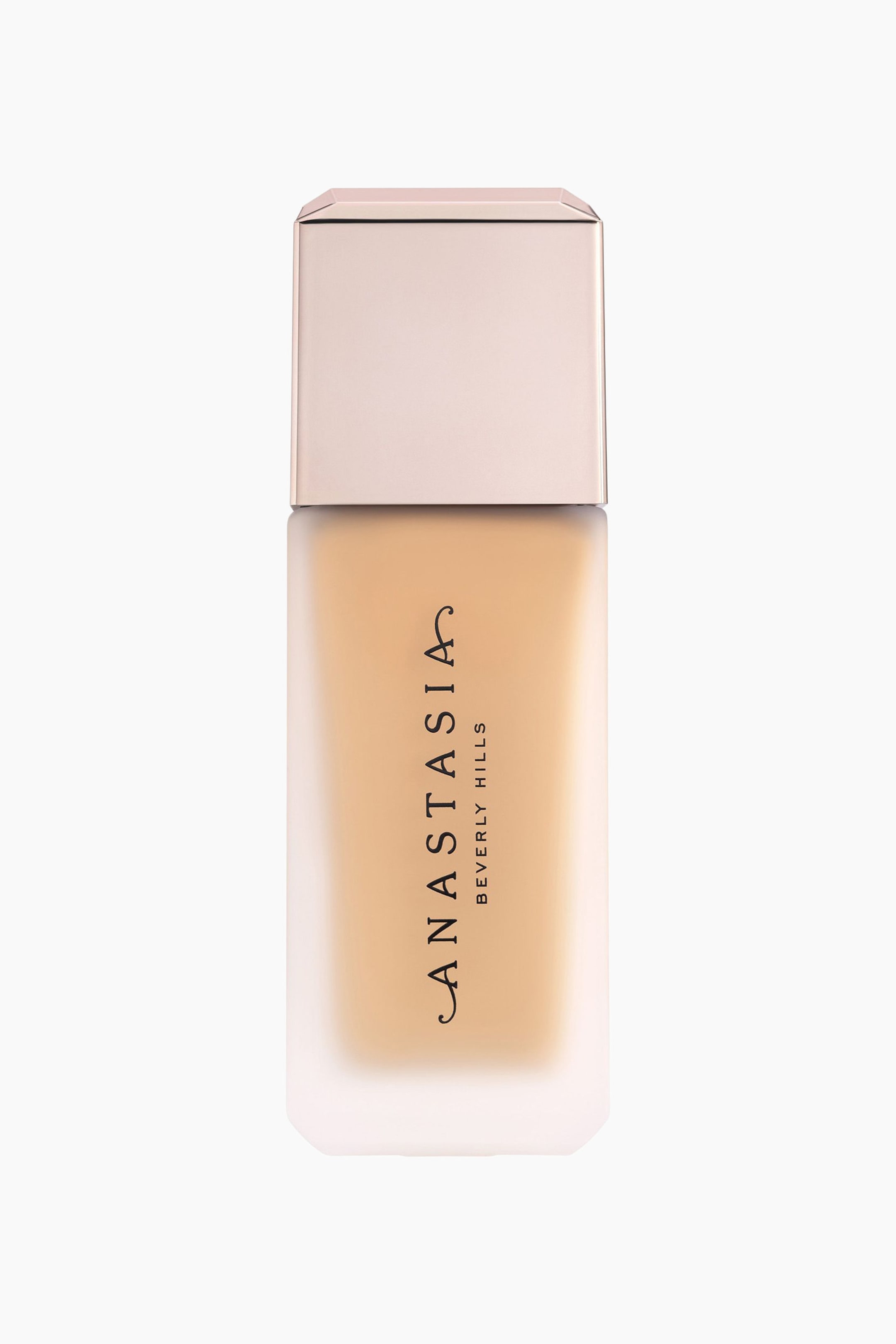 Se større billede: En rektangulær foundationflaske har en nederste sektion i frostet glas, der indeholder en lys beige væske. Flasken fremviser en roseguld-metalhætte, og mærkenavnet "ANASTASIA BEVERLY HILLS" er trykt lodret på forsiden.