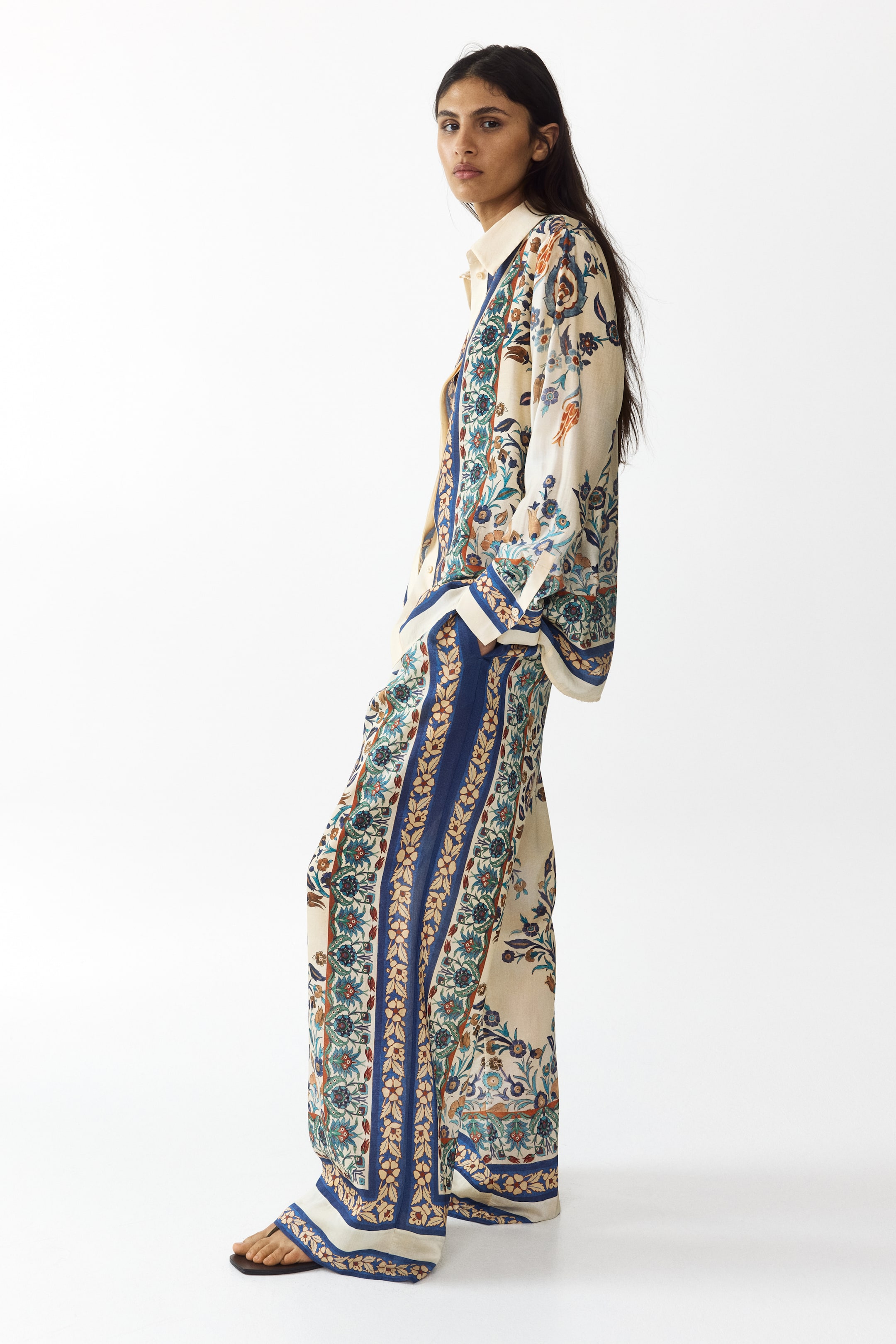 View larger image: The model is wearing an oversized shirt crafted from a printed viscose-blend weave. It includes a collar, hidden buttons along the front, and long sleeves with buttoned cuffs, paired with matching printed trousers.