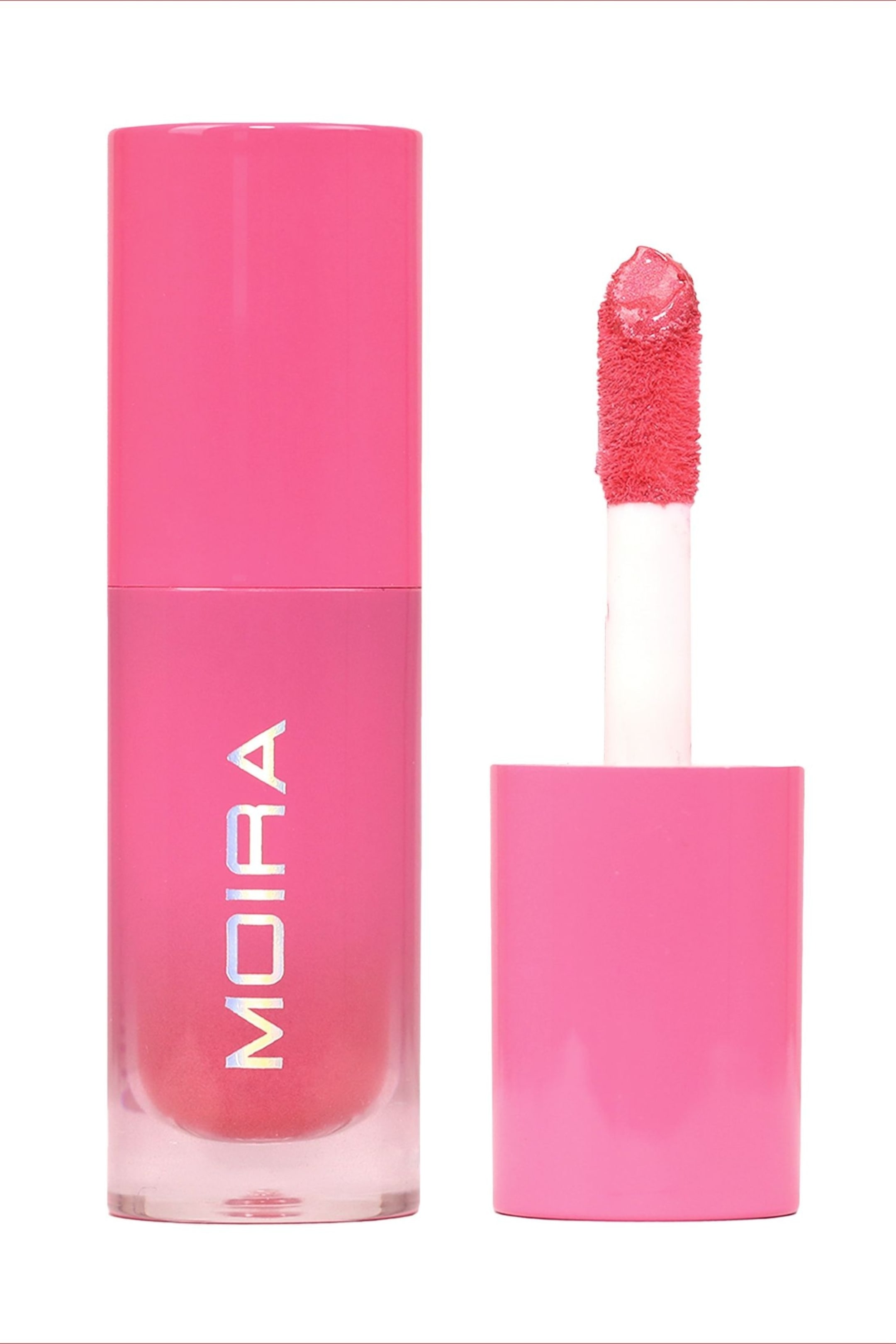 Vis større bilde: En rosa lipgloss vises, bestående av et klart sylinderformet rør og det løse lokket. Det klare røret inneholder en intens rosa gloss, med "MOIRA" trykt vertikalt i iriserende bokstaver, mens det matchende rosa sylinderlokket står oppreist ved siden av røret, med sin flokkbelagte applikatorspiss som stikker frem og holder den rosa glossen.