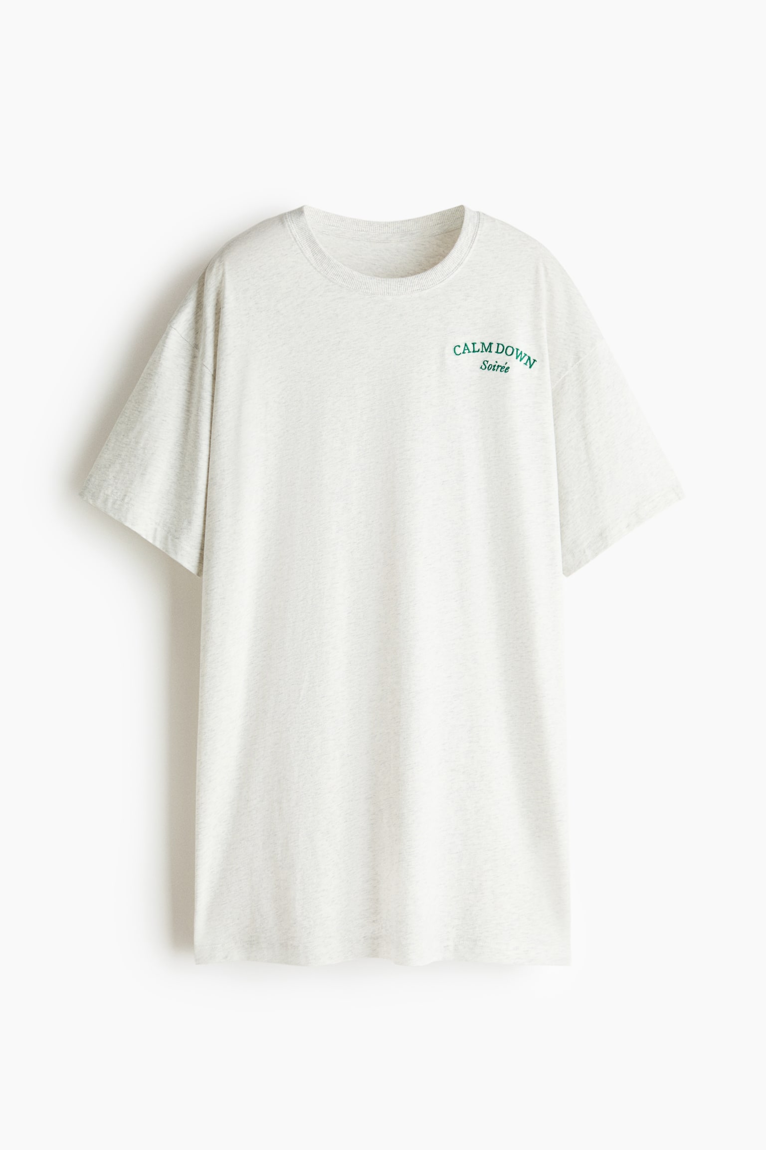 Een korte, losvallende nachthemd in lichtgrijze katoenen jersey wordt van voren getoond. Het heeft een groene "CALM DOWN Soirée" print op de borst, een geribbelde ronde hals, verlaagde schouders en ellebooglange mouwen.
