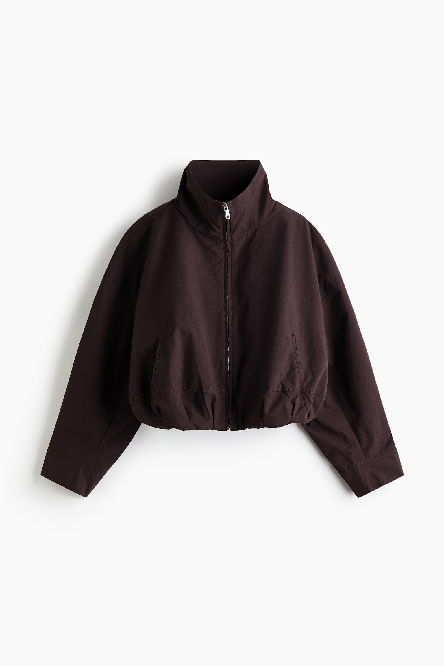 "A dark brown bomber jacket is presenting a front view, featuring a stand-up collar and a full silver zipper closure. It is displaying an elasticized hemline and two discreet front pockets, with wide, long sleeves ending in plain cuffs." - 1