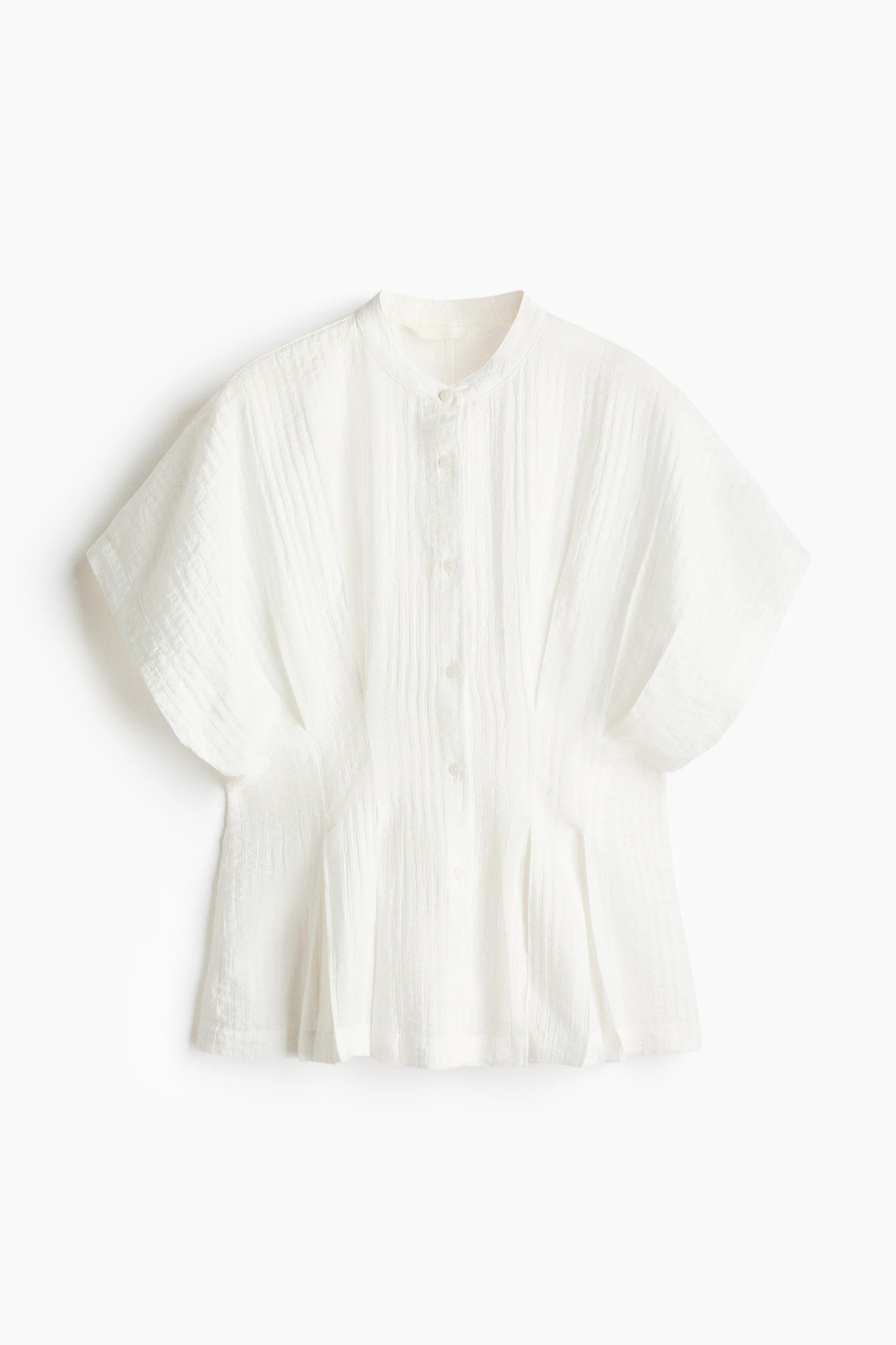 View larger image: A white textured blouse is displaying its front, featuring a band collar and a button-front placket. It highlights short, wide sleeves, vertical pintucks along the front, and pleats flaring from the fitted waistline.