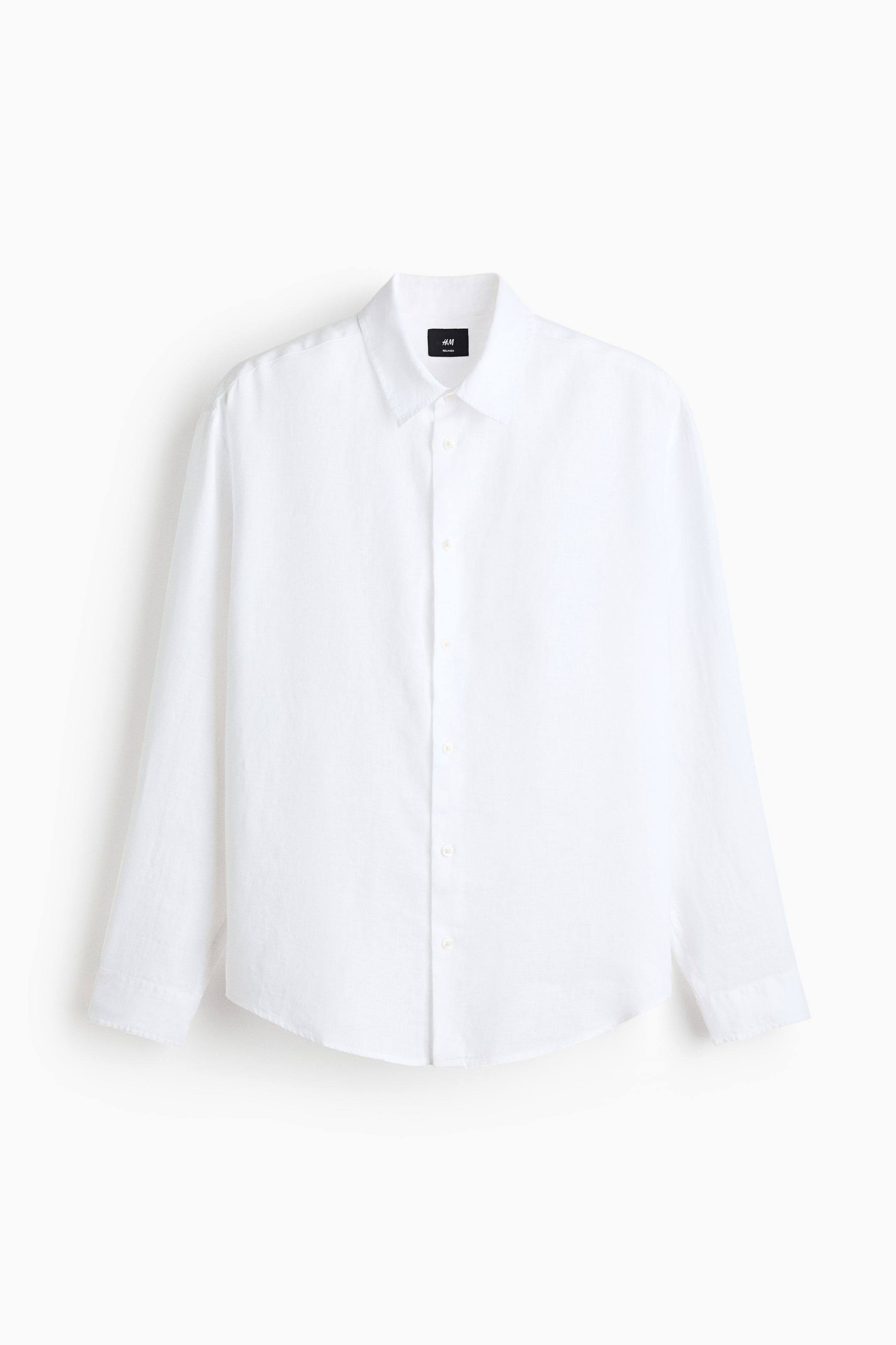 이미지 확대 보기: 흰색 긴 소매 셔츠가 앞면을 향해 있으며, 뾰족한 칼라와 밝은 색상의 버튼이 달린 전체 길이의 플래킷이 특징입니다. 긴 소매, 단추 하나로 된 커프스, 곡선형 밑단으로 디자인되었습니다.