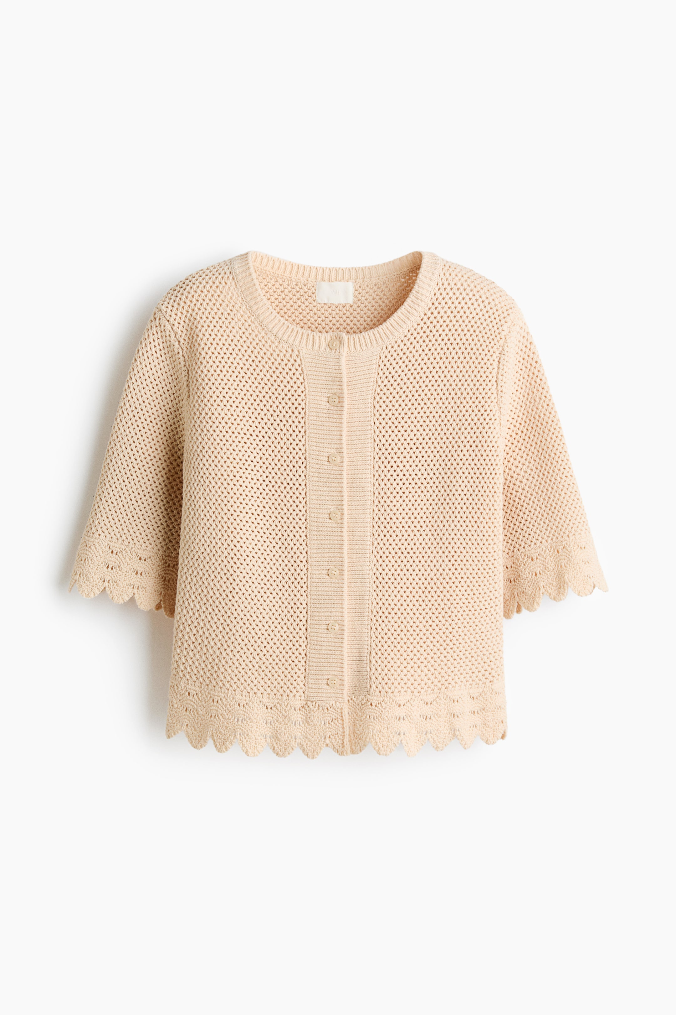 View larger image: A beige knitted cardigan is shown from the FRONT, featuring an open-knit construction throughout the body. It is designed with a round neckline, a button-front placket with six buttons, and three-quarter-length sleeves, finished with scalloped edges at the cuffs and hem.