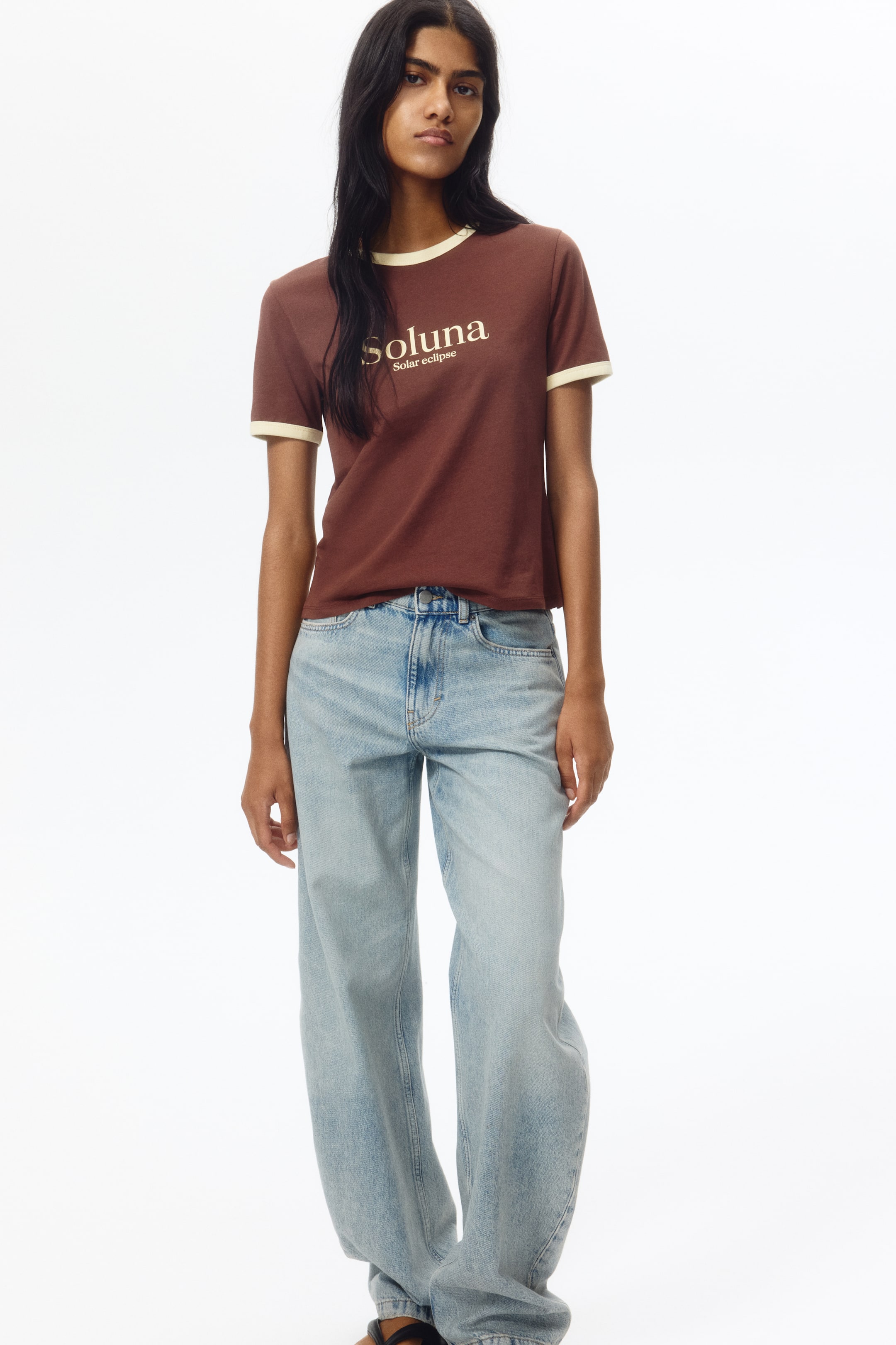 View larger image: Presenting a russet brown ringer t-shirt, adorned with off-white trim on its round neckline and short sleeves. The front showcases "Soluna" with "Solar eclipse" elegantly scripted below in matching off-white text.