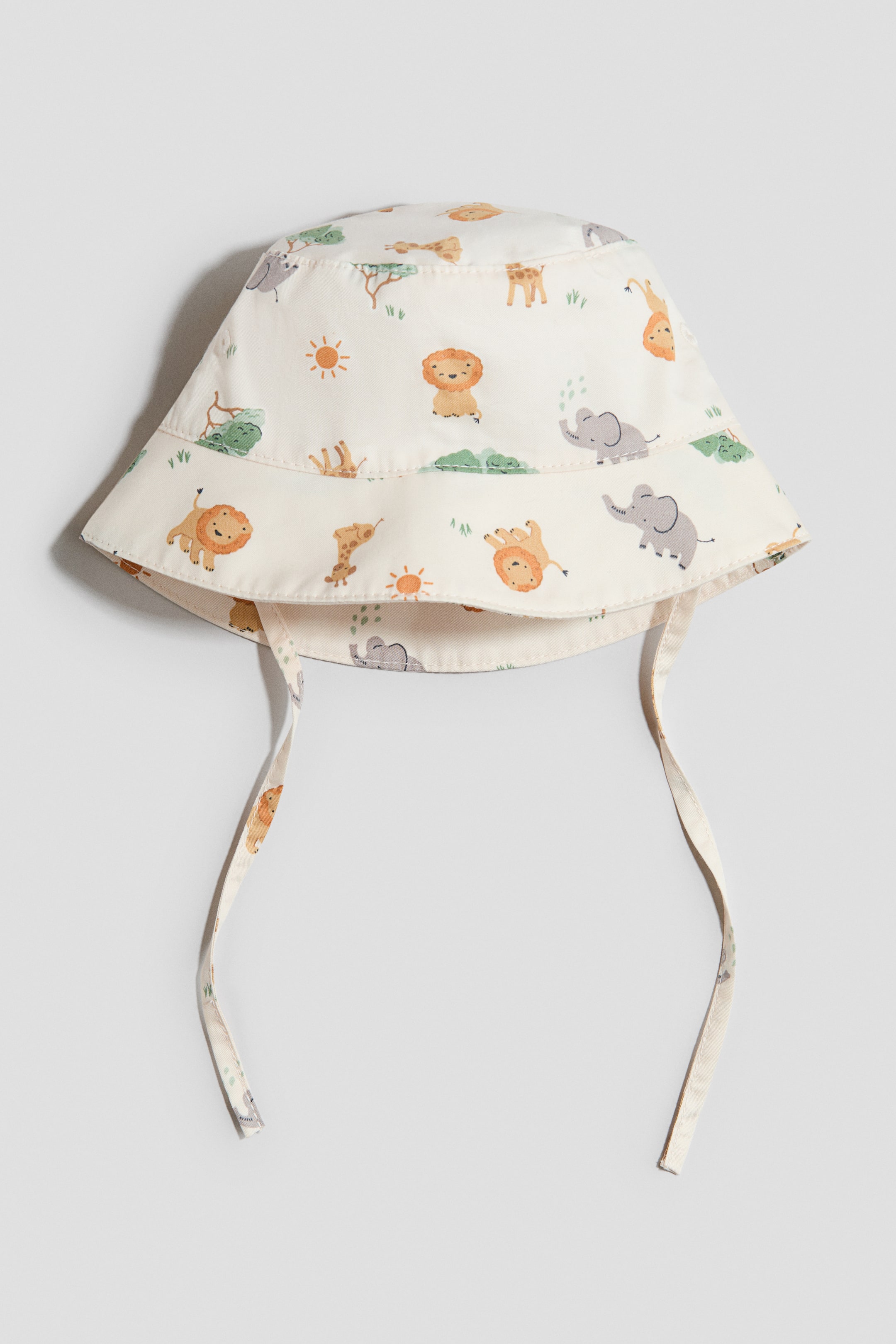 Ver imagem maior: Um chapéu de sol em tecido suave com laços sob o queixo é apresentado de frente, com uma base creme e um padrão colorido de animais de safari, incluindo leões, elefantes, girafas, árvores e sóis. É desenhado com uma coroa arredondada, aba inclinada para baixo e é forrado.