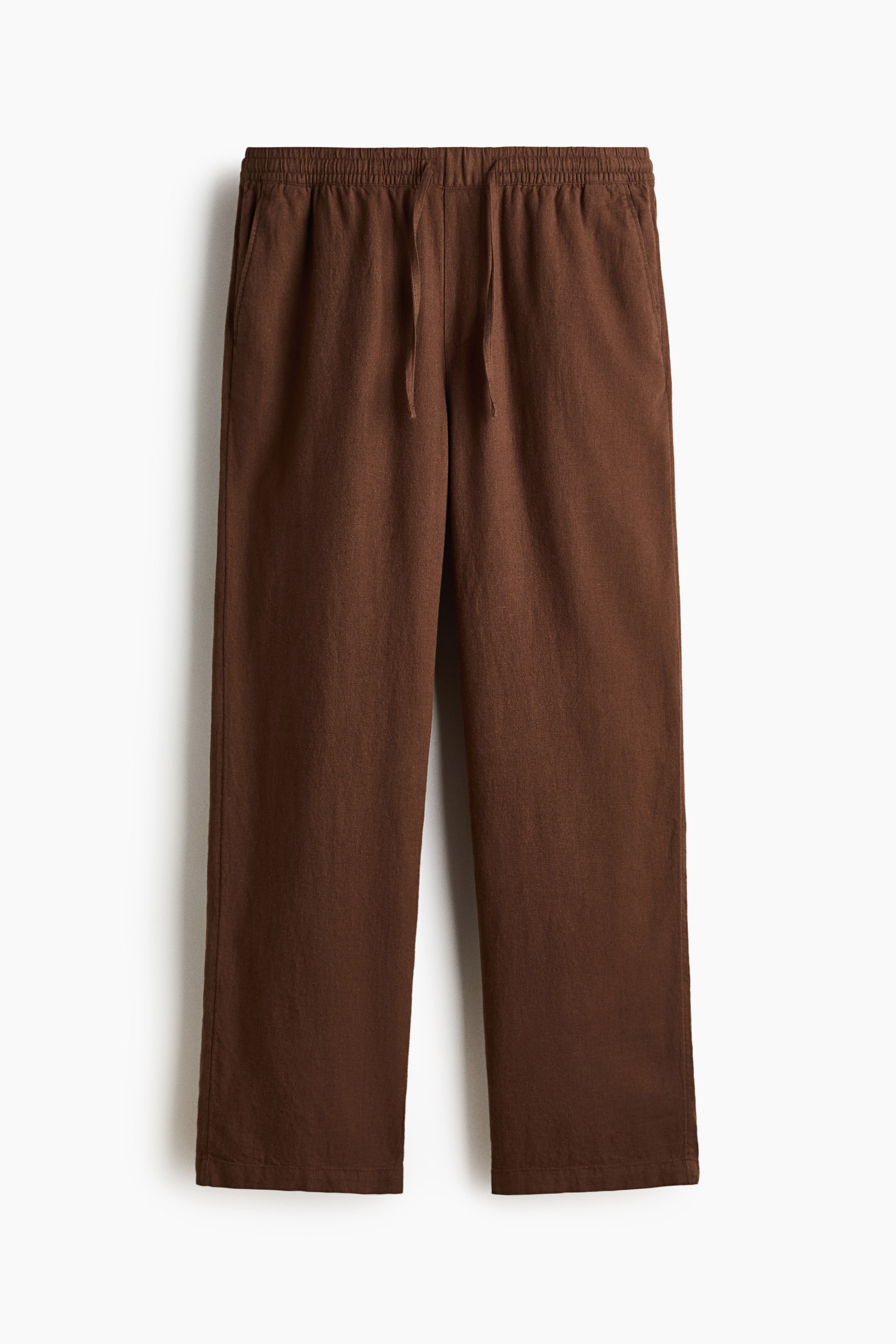 View larger image: Brown trousers showcase a soft weave, complete with a covered elasticated waist and a drawstring. Diagonal side pockets are prominently visible on the front, offering a relaxed fit.