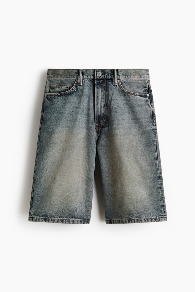 Distressed denim shorts are presenting in a frontal view, showcasing a faded blue-grey wash. They are featuring a button and zipper closure, belt loops, and front pockets, with visible contrast stitching. - 1