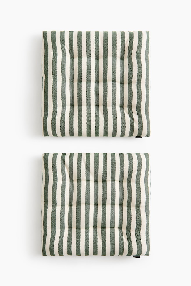 Two square padded seat cushions are shown from a top-down perspective, featuring a vertical dark green and off-white striped pattern. Both cushions display a quilted design with tufted quilted knots arranged in a grid across the surface. - 1