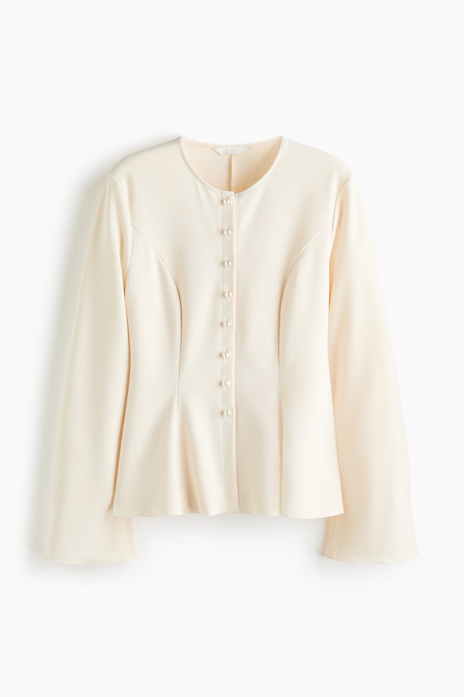 A cream-colored jacket is facing front, displaying a collarless round neckline and a front button closure with small, pearl-like buttons. It is showing structured princess seams that taper at the waist before flaring into a subtle peplum hem, alongside long, slightly wide-cut sleeves. - 1