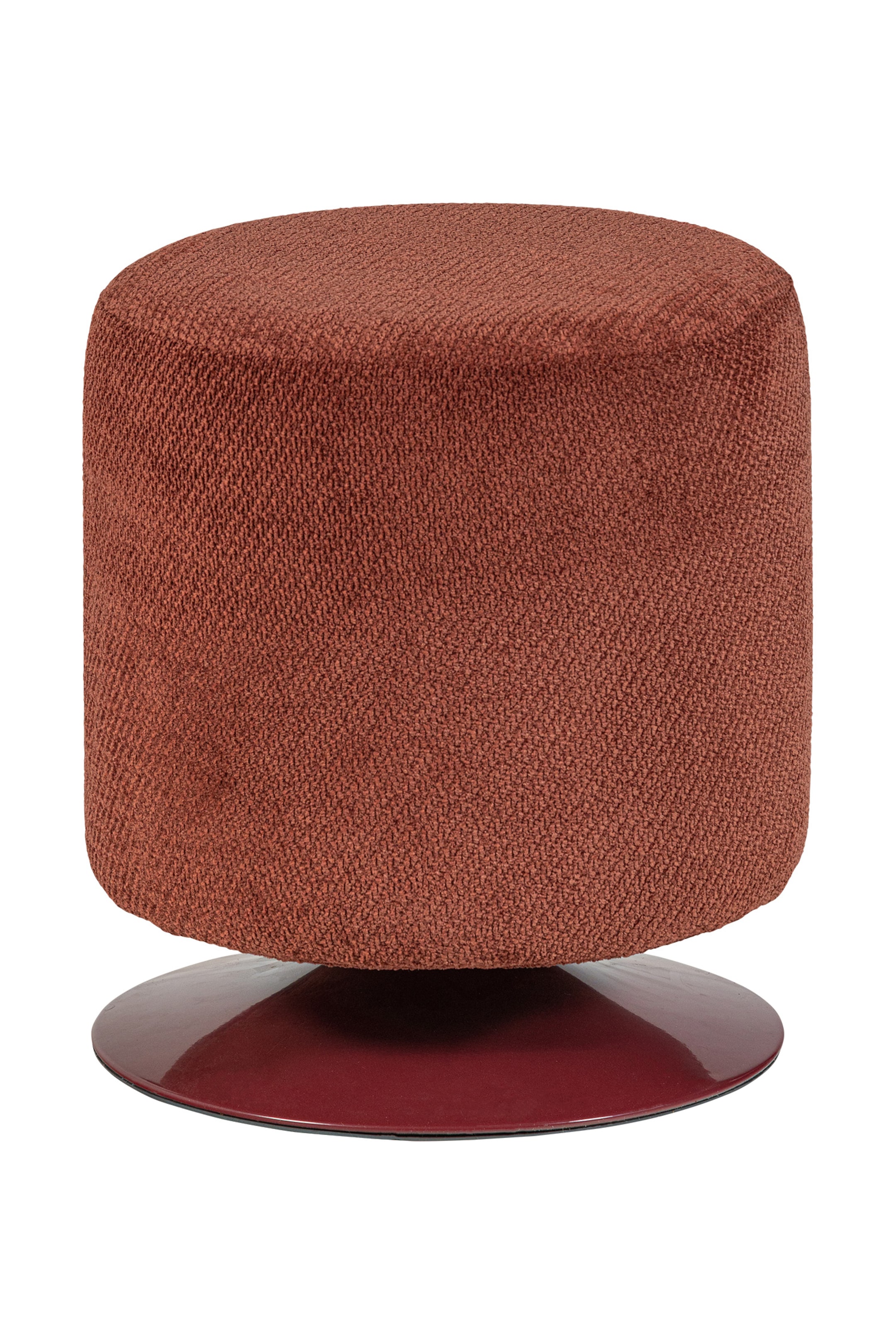 Zobacz większy obraz: Pufa posiada cylindryczne ciało tapicerowane tkaniną w kolorze rdzy, z płaską, okrągłą powierzchnią na górze. Spoczywa na błyszczącej, ciemnoczerwonej podstawie w kształcie dysku i jest lekko nachylona w prawo.