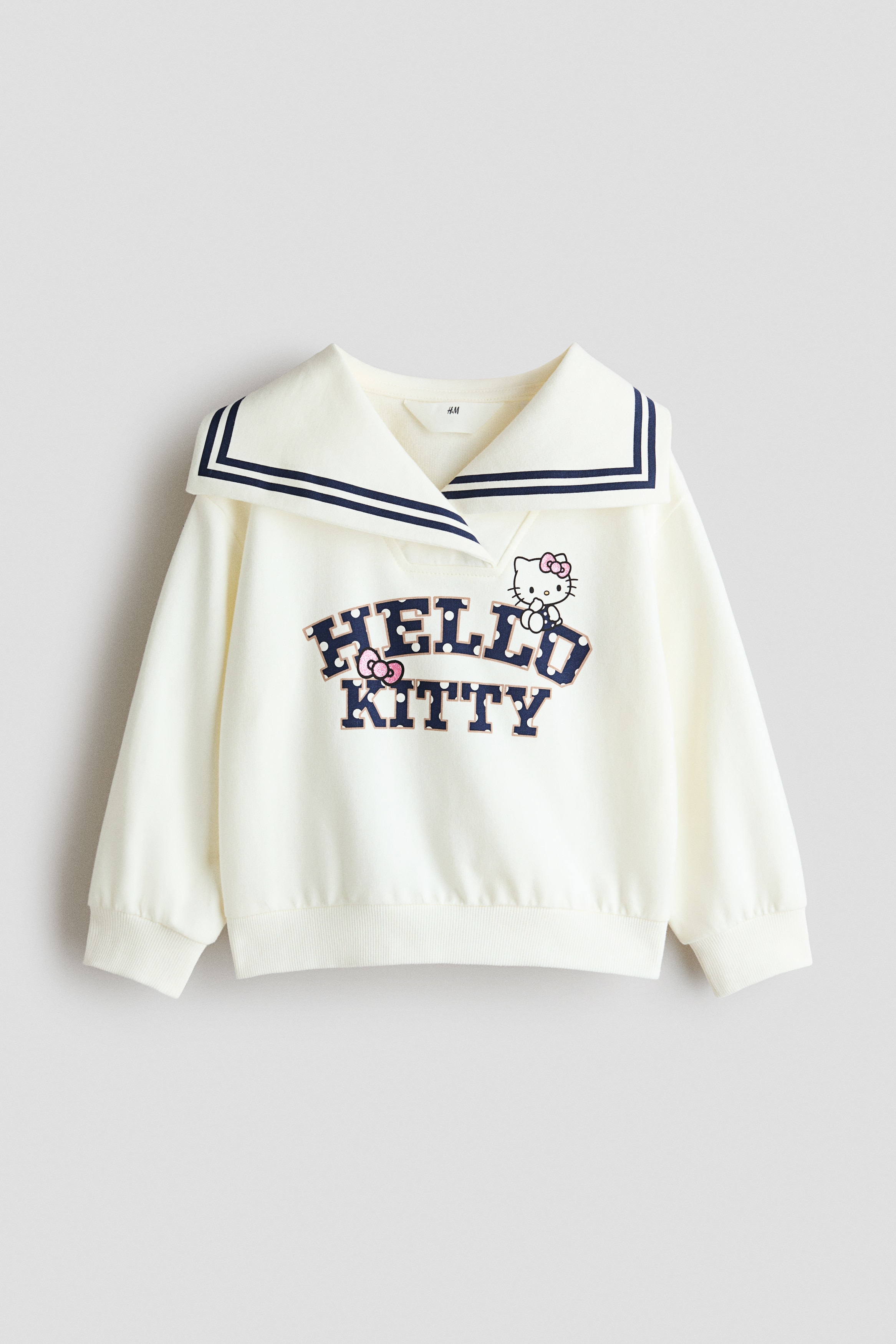 ã¢ãã«ã¯ããã¤ãã¼ãã«ã¼ã®ã¹ãã©ã¤ããå¥ã£ãå¤§ããªã»ã¼ã©ã¼ã«ã©ã¼ã¨ãHello Kittyãã®ããªã³ãã°ã©ãã£ãã¯ãç¹å¾´ã®ãªããã¯ã¤ãã®ã¹ã¦ã§ããã·ã£ããçç¨ãã¦ãã¾ããVããã¯ã®ã©ãããã­ã³ãããã­ããã·ã§ã«ãã¼ããªãä»ä¸ãã®ããªã ãåããã©ã¤ãã¦ã©ãã·ã¥ã®ããã ã¸ã¼ã³ãºã¨ãã¦ã¨ã¹ãã«å·»ãããã³ã¯ã®é·è¢ã·ã£ããåããã¦ãã¾ãã