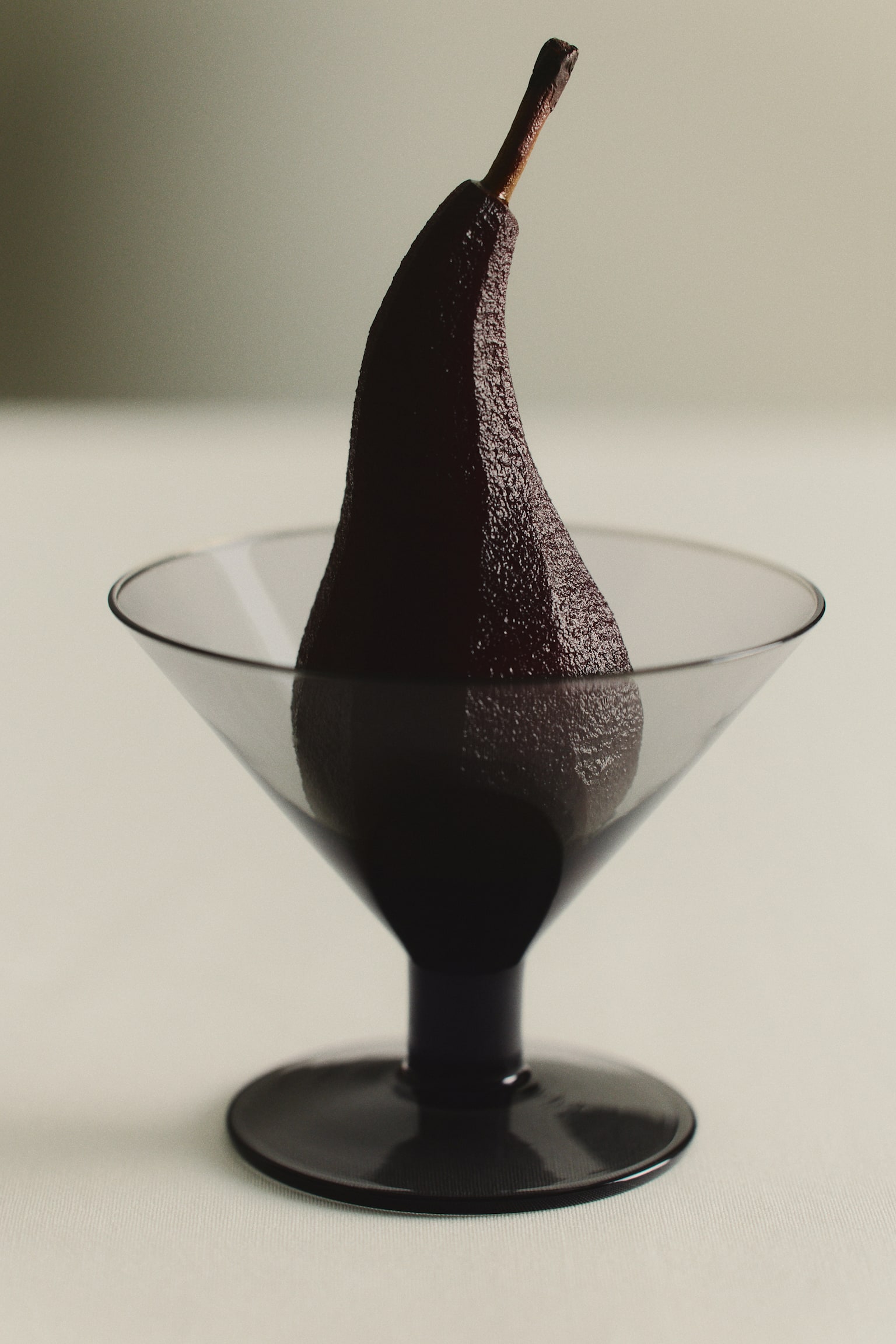 Quatre verres Ã  cocktail soufflÃ©s Ã  la bouche sont alignÃ©s horizontalement, face Ã  lâavant, mettant en valeur une finition translucide gris fumÃ©. Chaque verre prÃ©sente une coupe conique qui sâassombrit vers le bas, se prolongeant en un pied court et massif de couleur foncÃ©e, ainsi quâune base circulaire plate. - 1