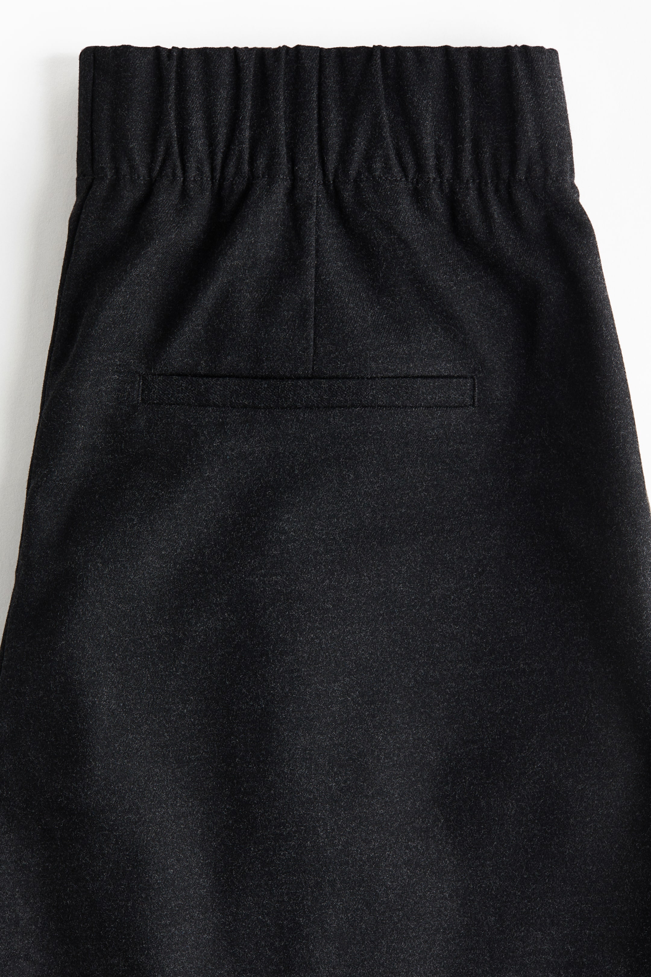 Näytä suurempi kuva: Tummanharmaat housut esittelevät joustavaa, kerättyä vyötärönauhaa. Yksi vaakasuora welt-tasku on keskitetty taakse, jota reunustavat pystysaumat, jotka ulottuvat alaspäin vyötärönauhasta.