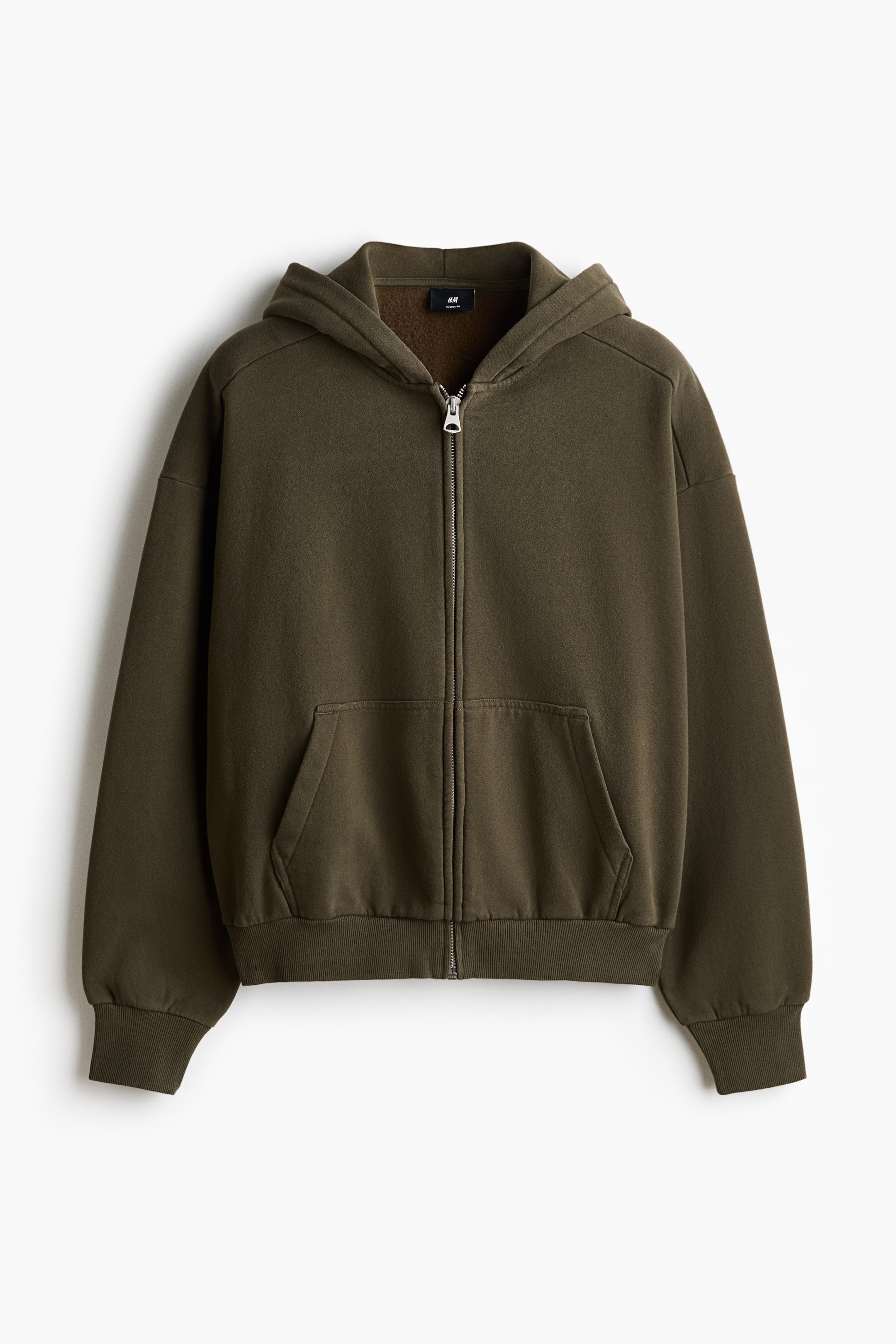 Xem ảnh lớn hơn: Một chiếc áo hoodie màu xanh ô liu có khóa kéo toàn bộ được hiển thị từ phía trước, với khóa kéo kim loại màu bạc, mũ trùm đầu gắn liền, tay áo raglan, túi kangaroo lớn và cổ tay áo cùng gấu áo có đường viền gân.
