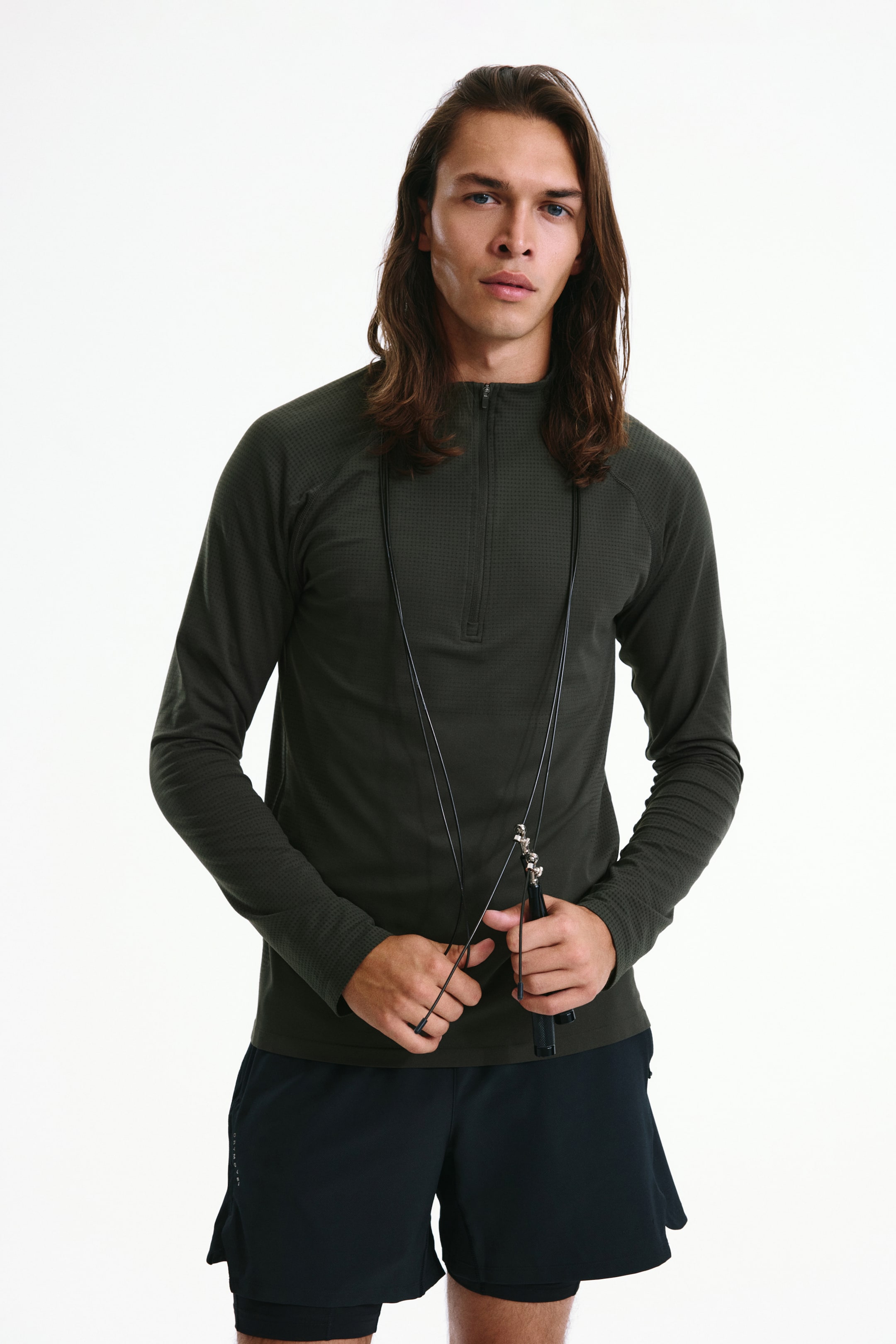 View larger image: The model is wearing a dark green muscle-fit zip-up sports top with DryMove, featuring a subtle textured pattern and long sleeves.
