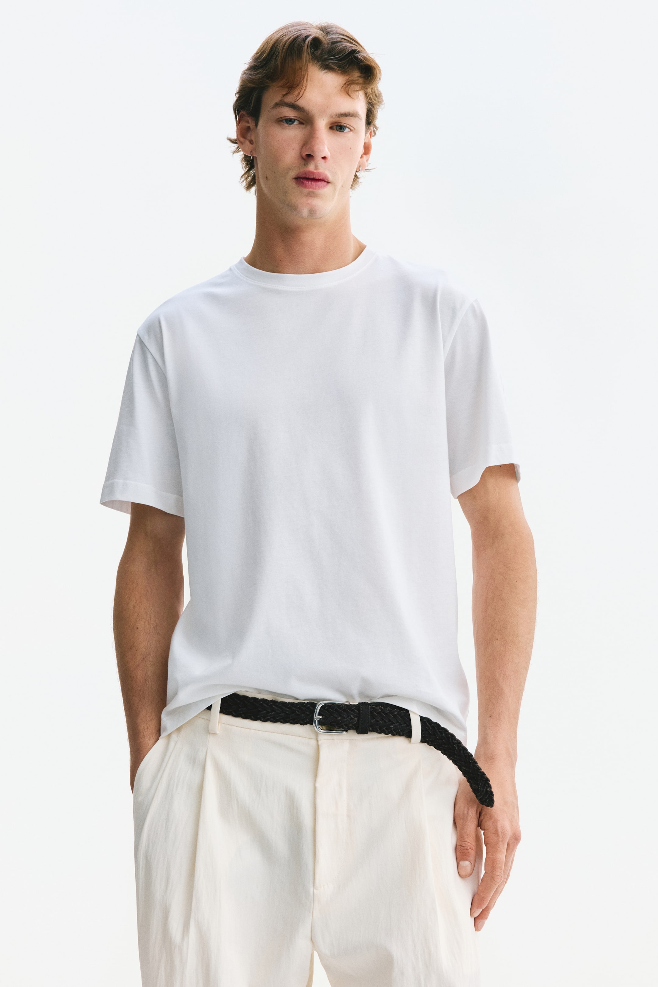 View larger image: Model tersebut memakai t-shirt putih dengan leher bulat dan lengan pendek. T-shirt ini mempunyai potongan biasa dan hem lurus.