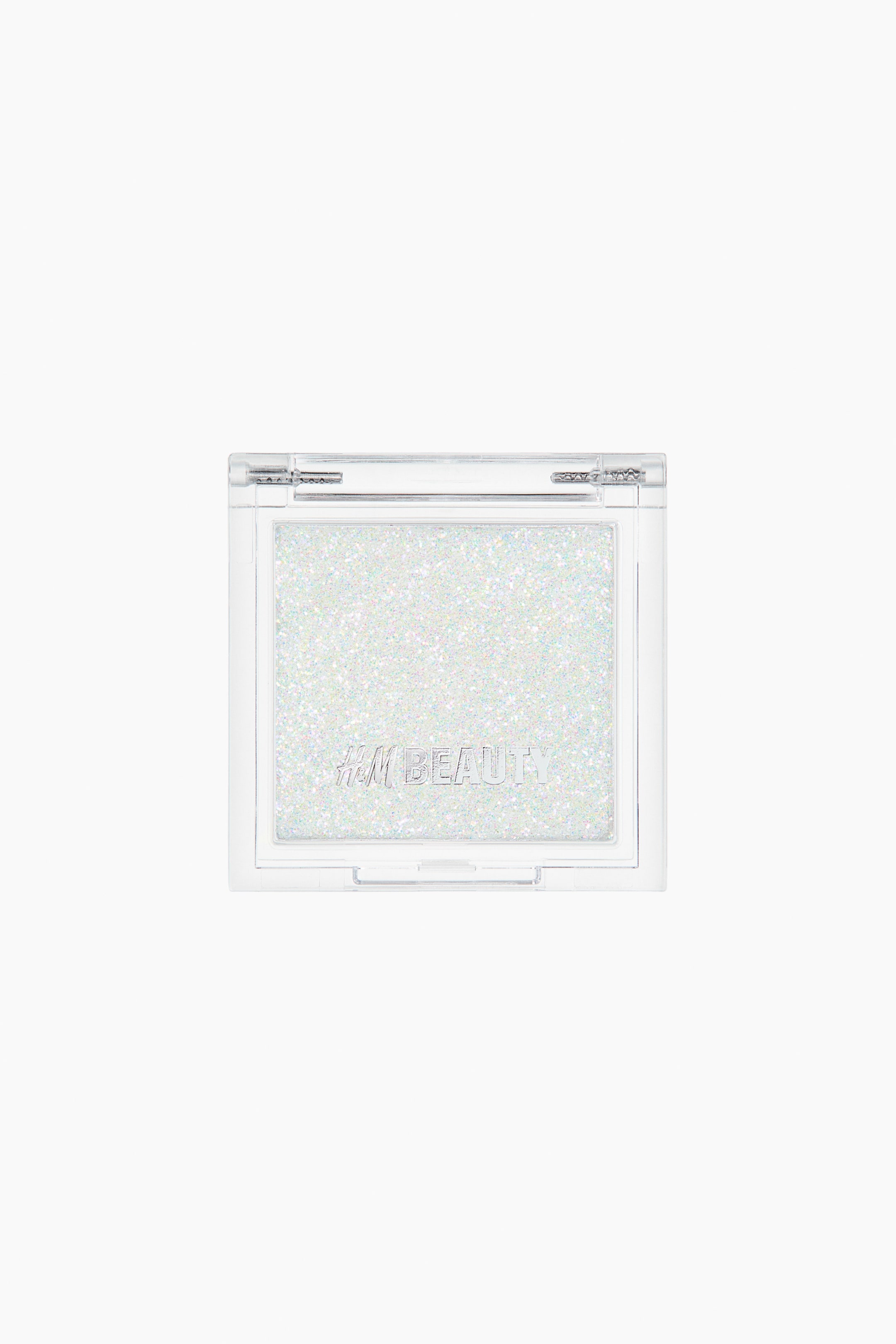 Zobacz większy obraz: Cień do powiek prezentowany jest w przezroczystym, prostokątnym kompaktowym opakowaniu z przezroczystą pokrywką, skierowanym do przodu. Cień do powiek ma połyskujący, iryzujący biały kolor z wielokolorowymi drobinkami brokatu, a na jego powierzchni widnieje wytłoczony napis "H&M BEAUTY".