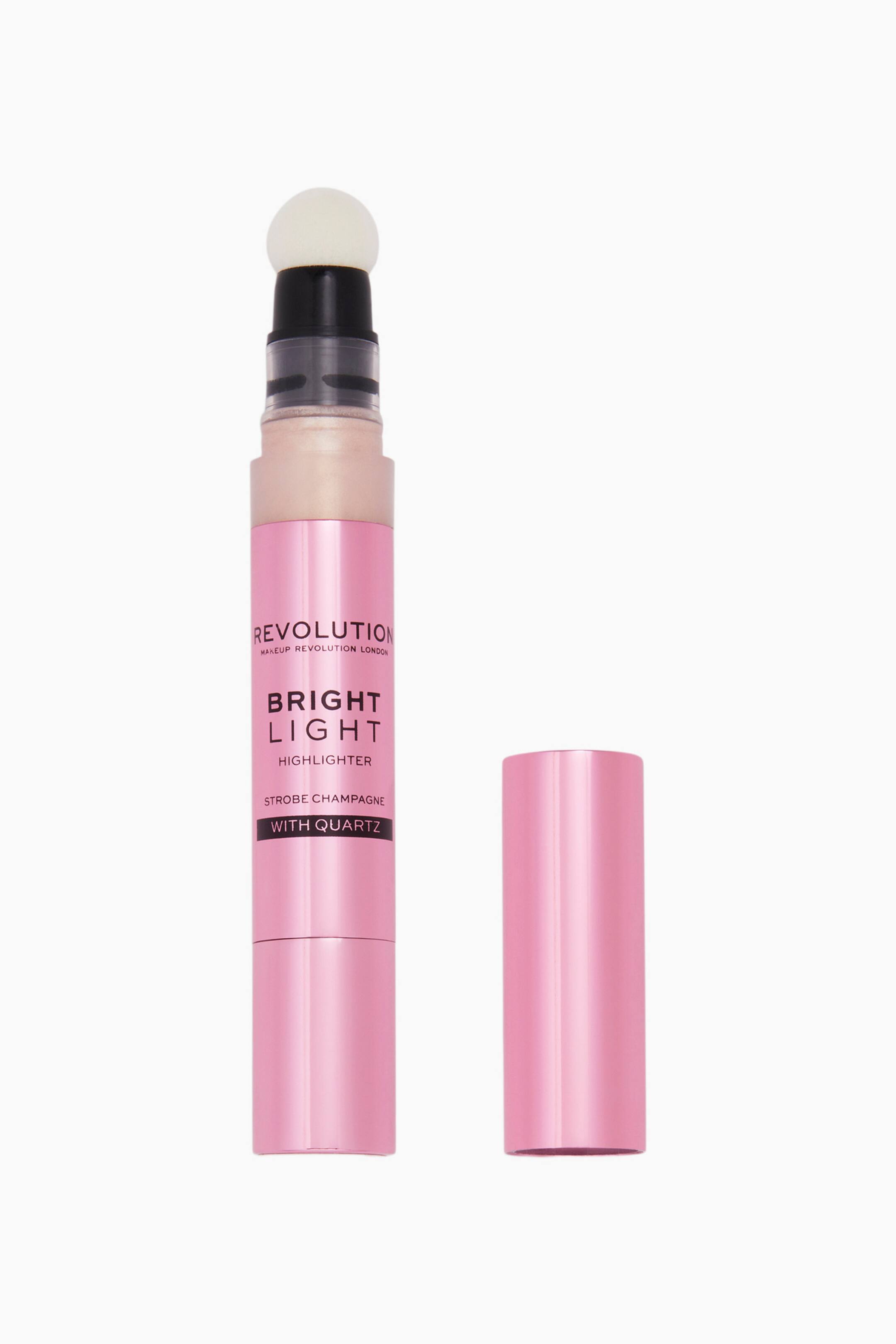 Größeres Bild ansehen: Ein unverschlossener Revolution Bright Light Highlighter-Stift steht aufrecht neben seiner abgenommenen rosa Metallkappe und zeigt oben einen abgerundeten weißen Schwammapplikator. Der rosa zylindrische Körper trägt schwarzen Markenaufdruck, während ein transparenter Abschnitt nahe dem Hals das champagnerfarbene Flüssigprodukt im Inneren sichtbar macht.