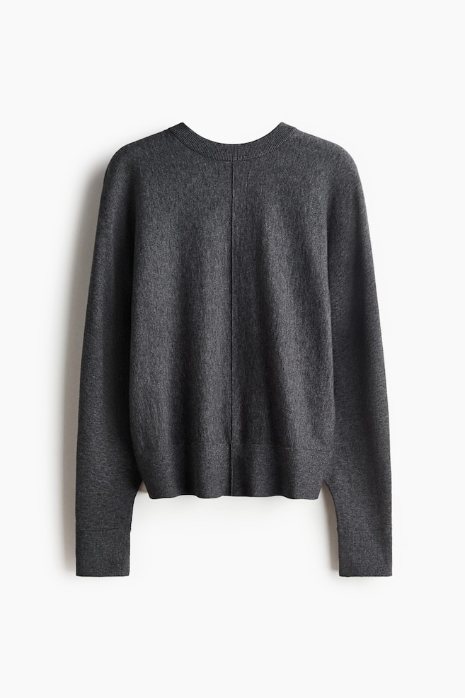 Un chandail en tricot gris foncé est présenté de dos. Il est doté d'un col rond côtelé, de manches longues avec poignets côtelés et d'un ourlet côtelé avec de petites fentes latérales. Une couture verticale descend le centre du dos. - 1