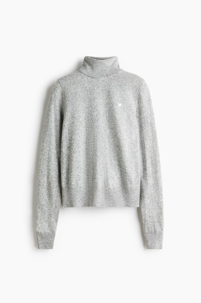 A heather grey knit turtleneck sweater is hanging facing the front, showcasing a ribbed collar, ribbed cuffs, and a ribbed hem. A small white heart logo is detailing the left chest of the soft-textured fabric. - 1
