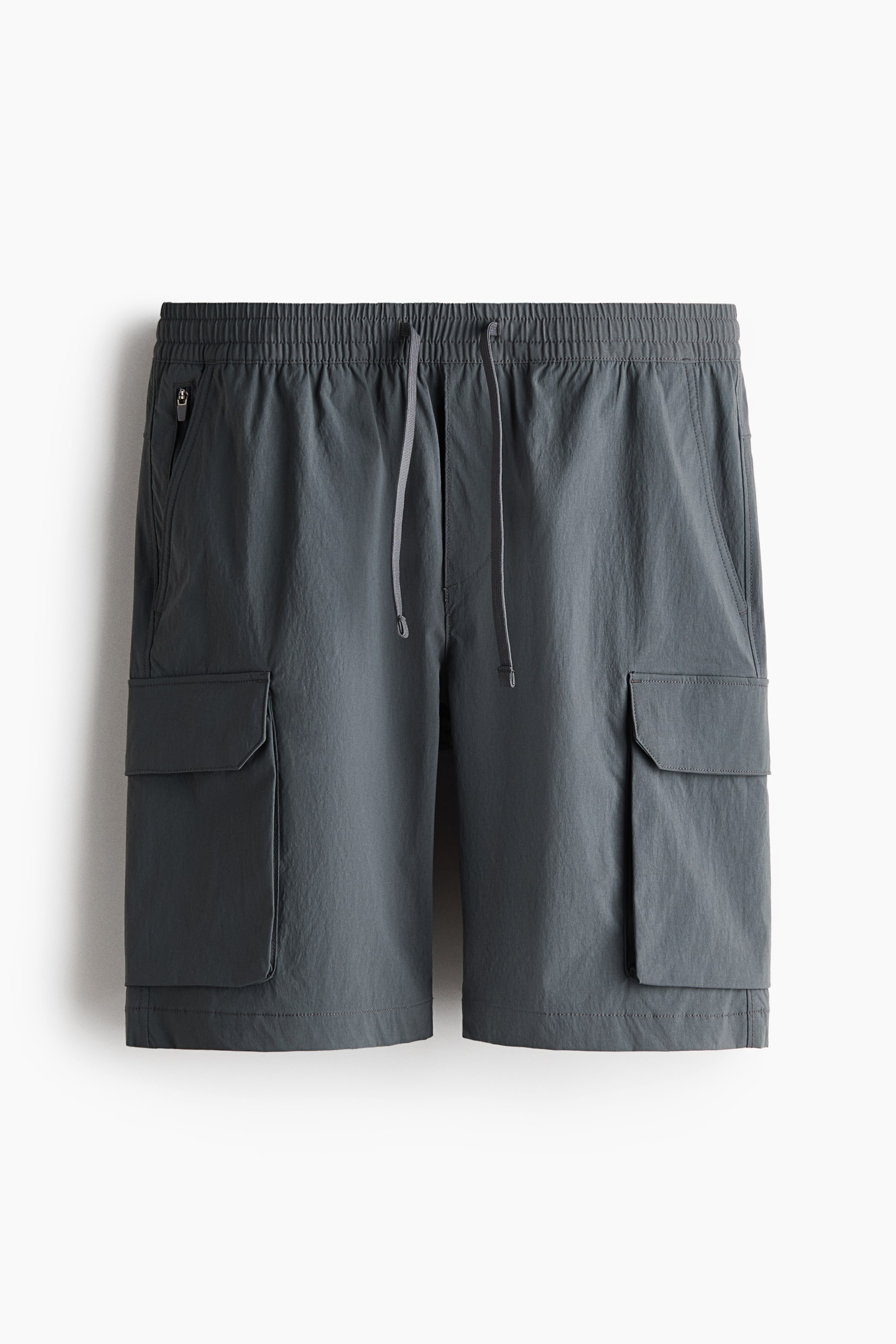 View larger image: The dark grey shorts are showcased from the front, featuring an elastic waistband with a central drawstring. They include two side pockets, one with a zipper closure, and two flap cargo pockets, one positioned on each leg.