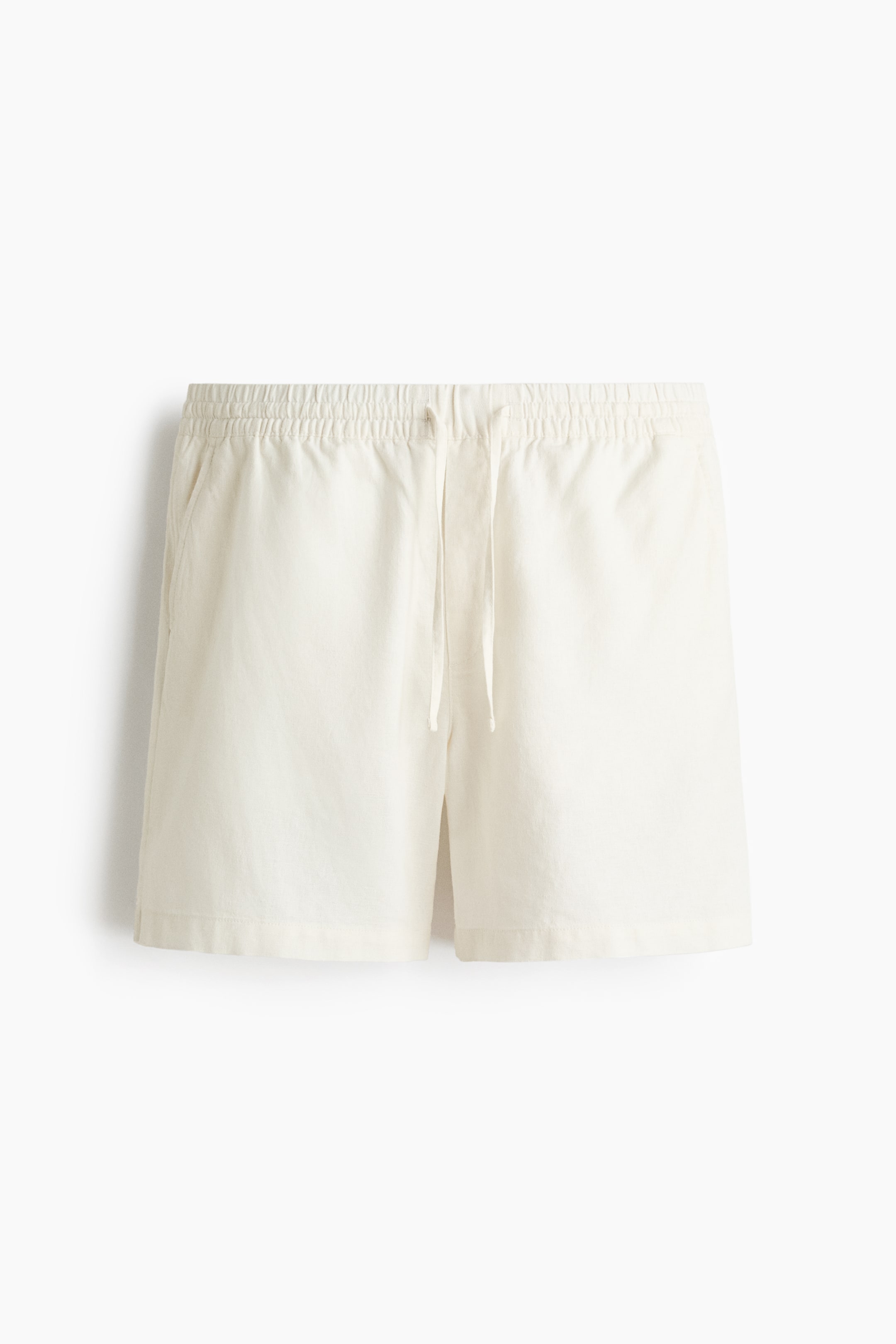 View larger image: Off-white shorts are shown in a FRONT view, featuring an elastic waistband with a center drawstring tie. Side pockets are visible on both sides, and the shorts finish with a straight hem.