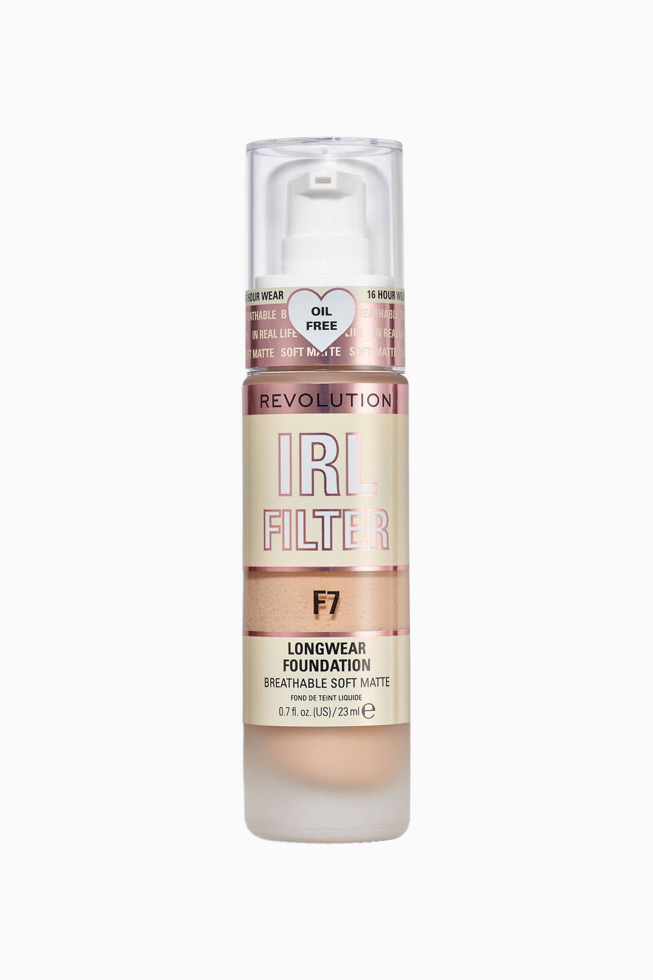 Größeres Bild ansehen: Der Revolution IRL Filter Longwear Foundation steht aufrecht und zeigt nach vorne eine zylindrische Flasche mit einem mattierten Glasboden, durch den eine beige flüssige Foundation sichtbar ist. Die Flasche verfügt über ein cremefarbenes Etikett mit metallisch-pinker und schwarzer Beschriftung und ist mit einem weißen Pumpspender unter einer transparenten Kunststoffkappe versehen.