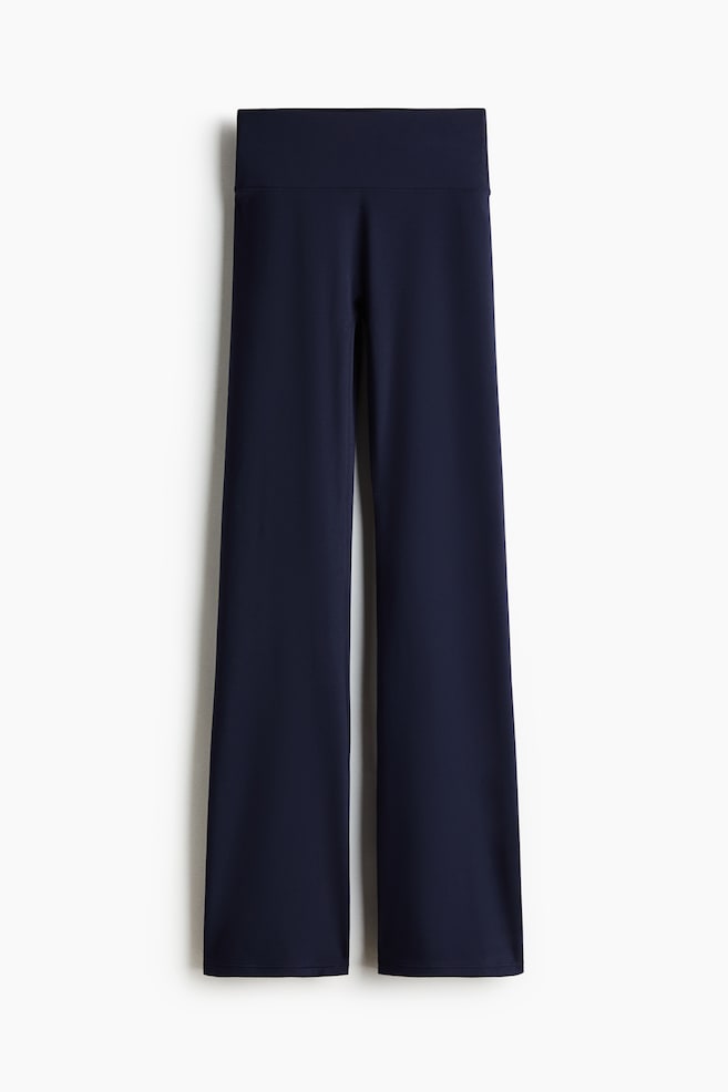 Flared yoga leggings with SoftMove? are dark blue, facing FRONT. They feature a wide, high-rise waistband and legs that flare from the knee down to the hem. - 1