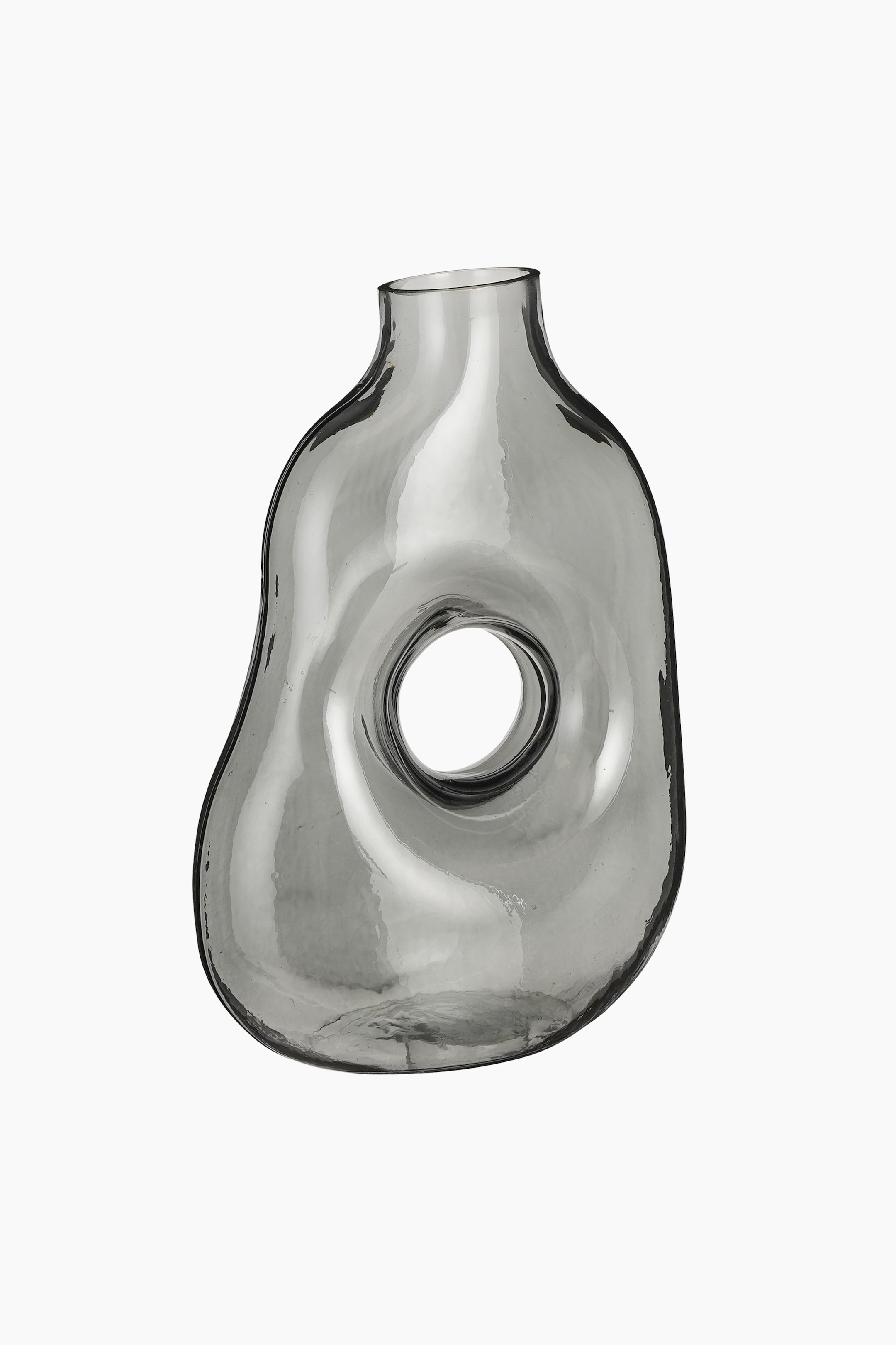 Grotere afbeelding bekijken: Een rokerig grijze glazen vaas presenteert een onregelmatige, organische vorm met een smalle hals en een bredere buik. Een grote ronde opening doorboort het midden van de buik.