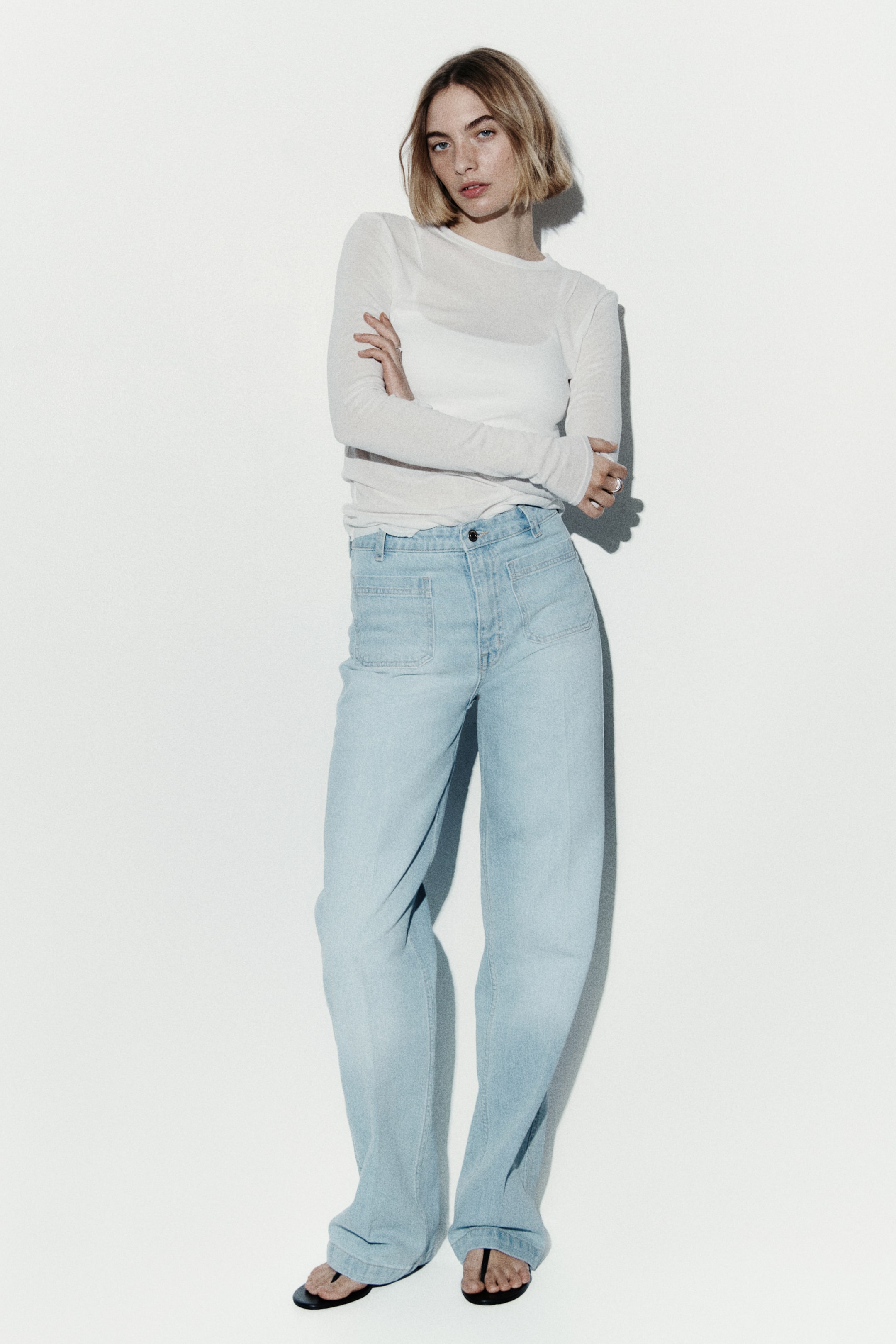 Grotere afbeelding bekijken: De lichtgewassen jeans met wijde pijpen hebben een hoge taille met een knoopsluiting en ritssluiting. Ze zijn voorzien van grote rechthoekige opgestikte zakken aan de voorkant en hebben een ontspannen pasvorm, die iets bij de enkels samenkomt.