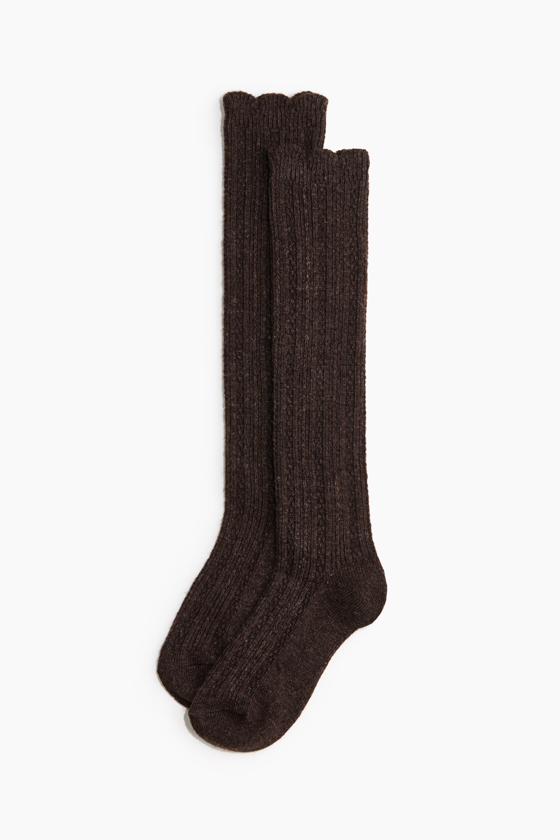 View larger image: Knee-high socks in a dark brown, textured ribbed knit are lying flat, overlapping slightly to show their shape. The socks feature elasticised, scalloped cuffs at the top, with a defined heel and toe structure.