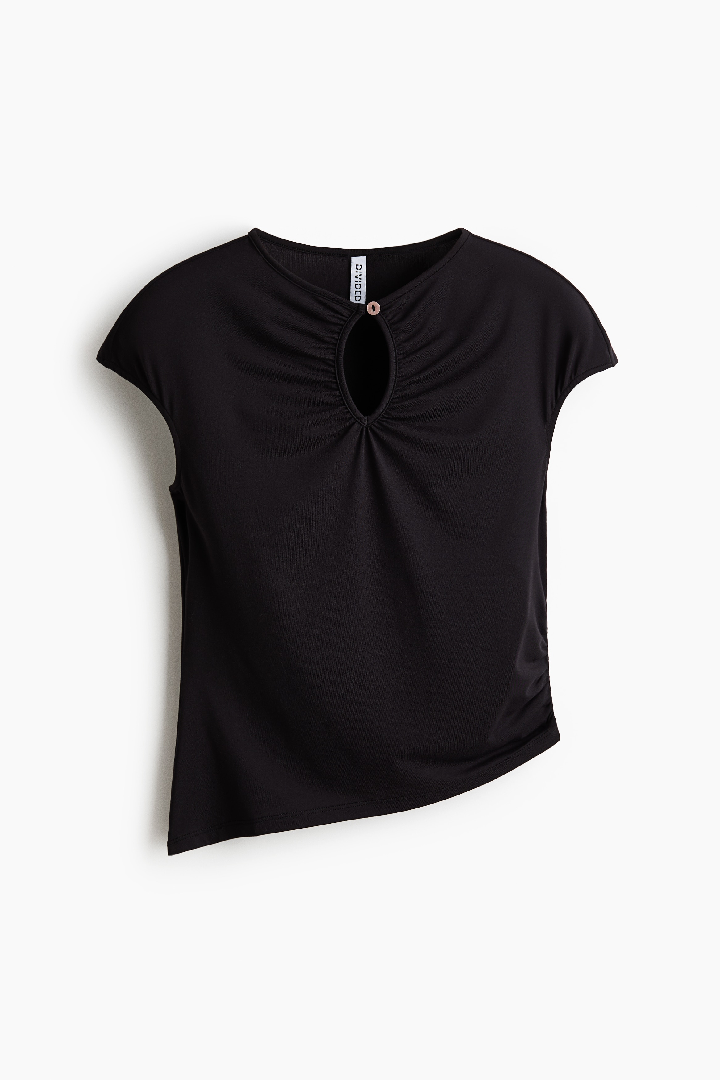 The model is wearing a fitted dark brown jersey top featuring cap sleeves, a front keyhole cut-out with gathered detailing, and a button fastening at the neckline. The top has an asymmetrical hem and is paired with dark trousers.