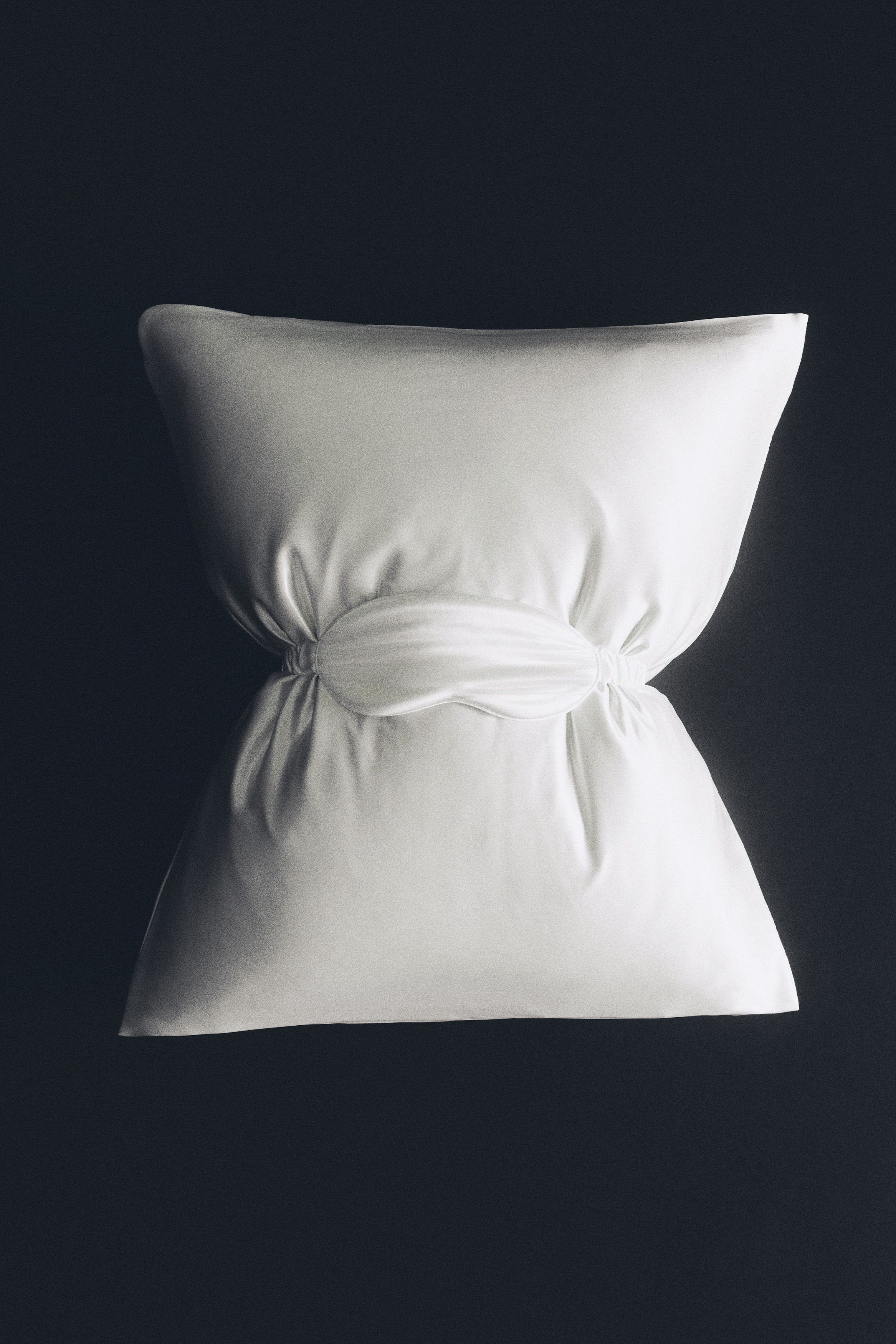 A silk sleep set is being displayed from the front in a flat-lay view, featuring an off-white padded sleep mask with a gathered elastic strap and a matching rectangular silk pillowcase. Below them, a beige rectangular gift box is shown with the printed text "SILK SLEEP SET" along the bottom edge.