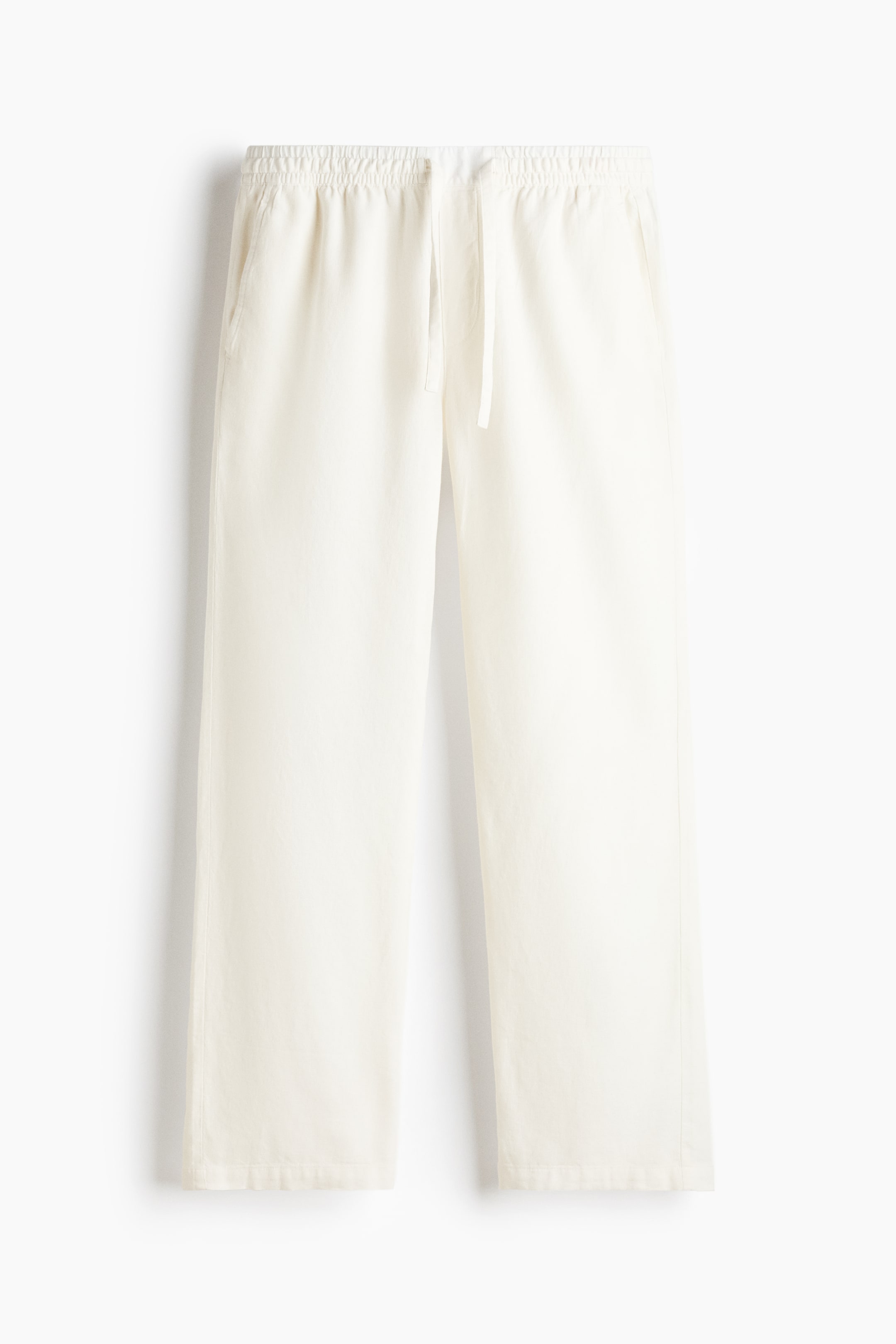 View larger image: These off-white trousers are shown from the front, featuring a relaxed, straight-leg silhouette with an elasticated waistband and a hanging drawstring. The trousers display side seam pockets and a lightweight, textured fabric.